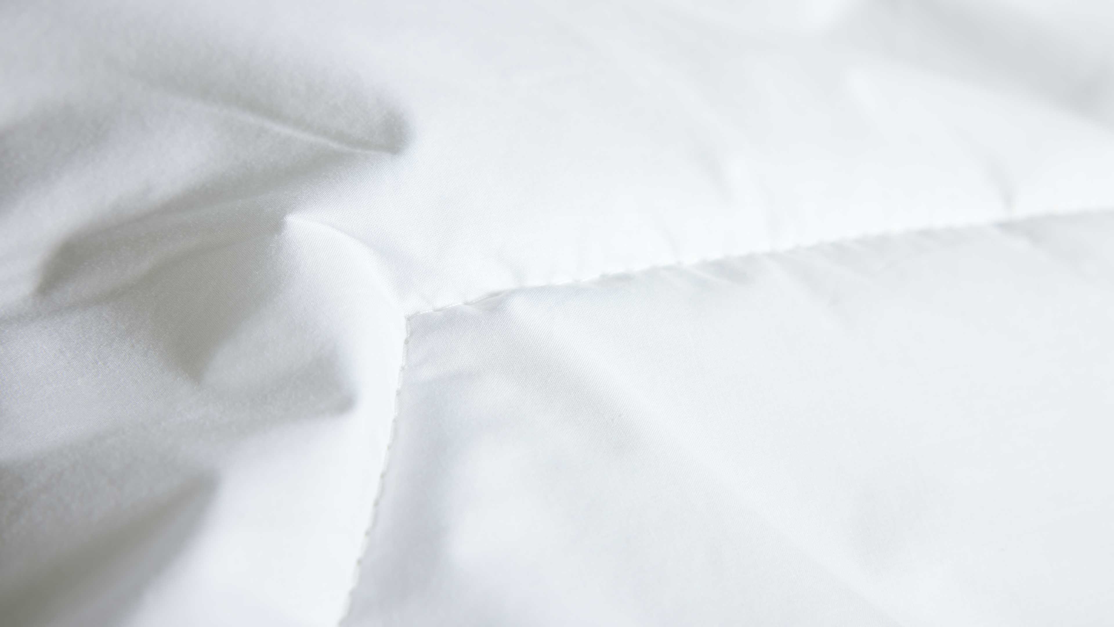 Ein weißer, gesteppter Stoff weist quadratische Nähte und leicht gewölbte, gepolsterte Kammern auf.