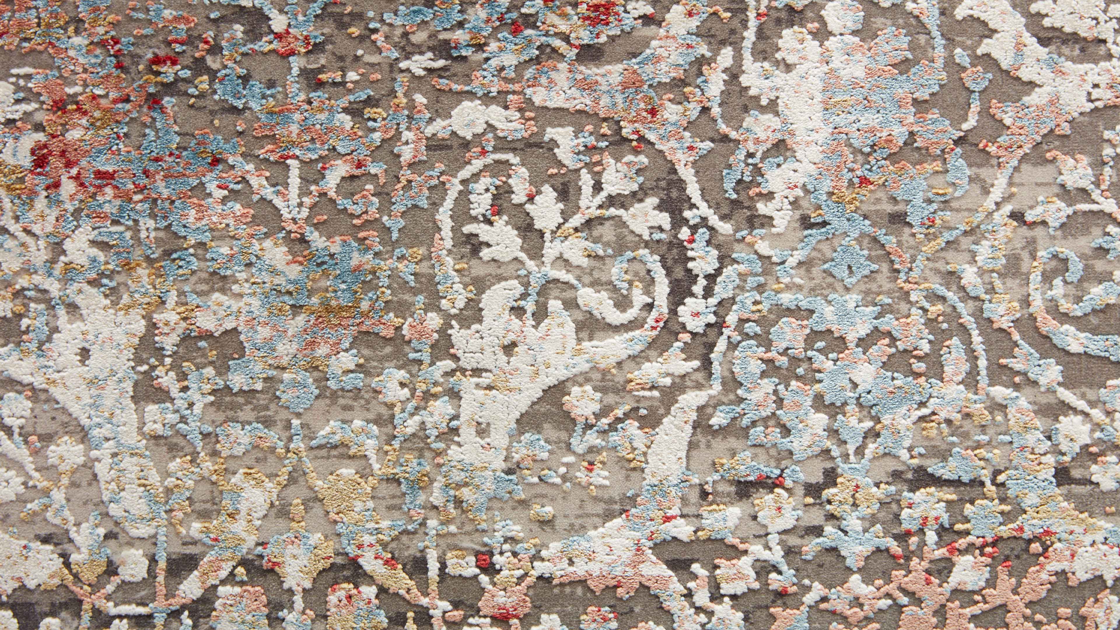 Teppich mit reliefartigem Blumenrankenmuster in Weiß, Hellblau, Rosa, Gold und kleinen roten Akzenten auf graubraunem Grund.