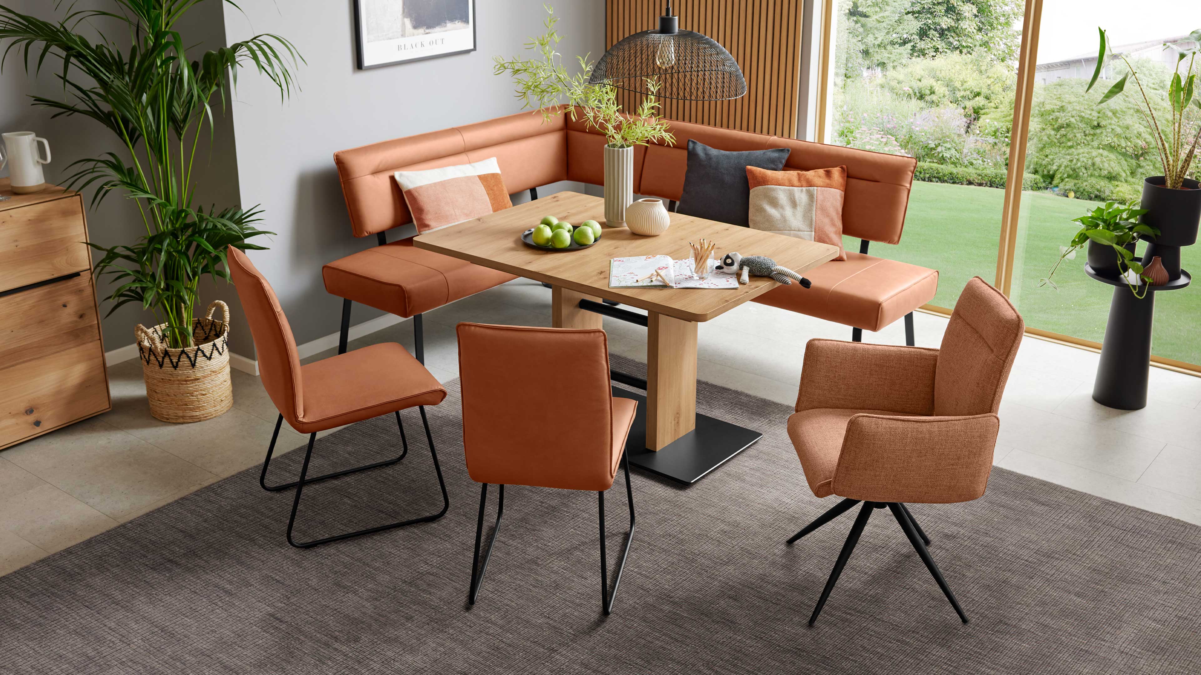 Orangebraune Eckbank um einen rechteckigen Holztisch, drei Seitenstühle und ein drehbarer Polsterstuhl auf grauem Teppich.