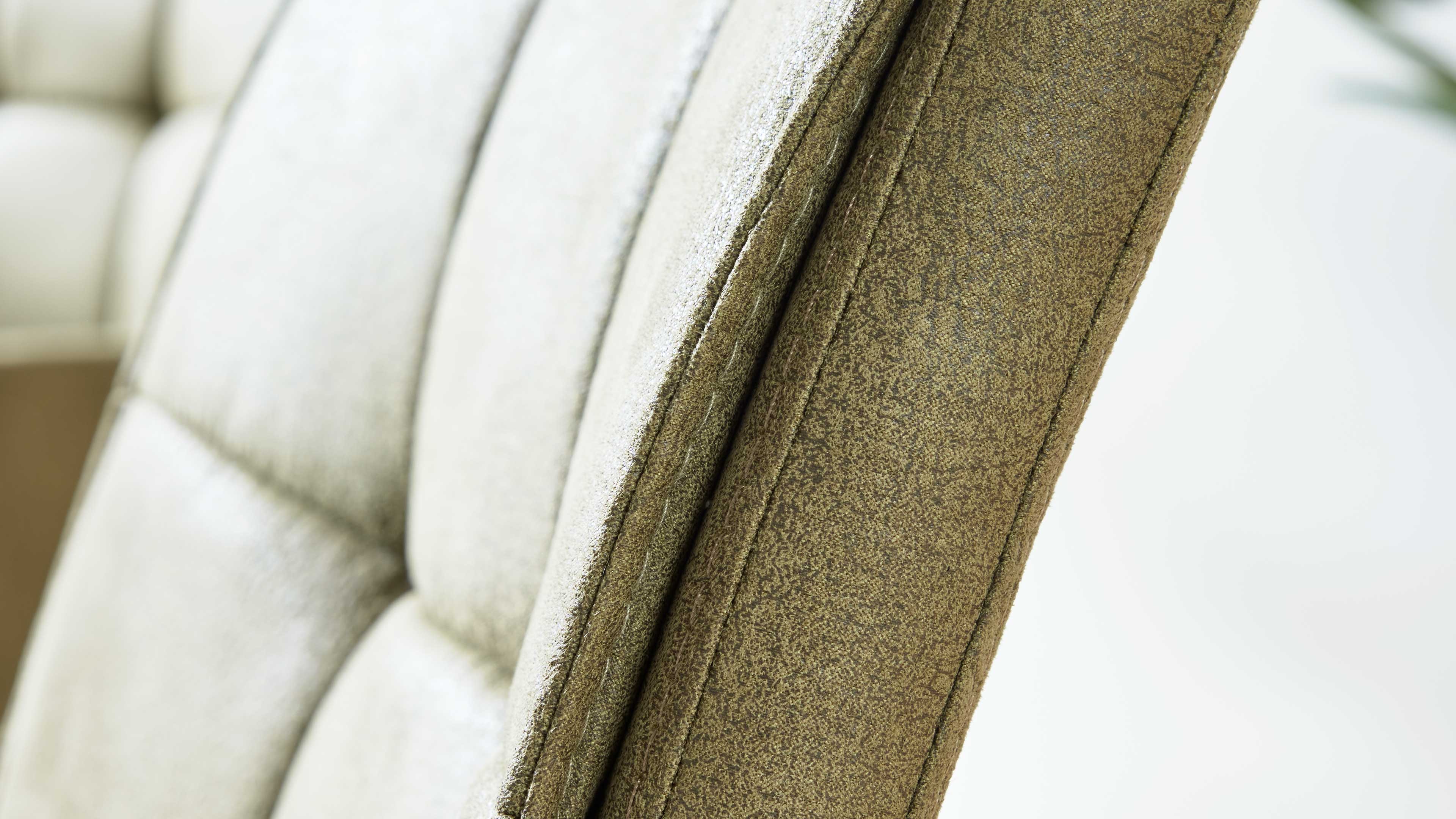 Nahaufnahme der Rückenlehne eines gepolsterten Stuhls mit strukturierter olivgrüner Bezugsware und sichtbaren Ziernähten.