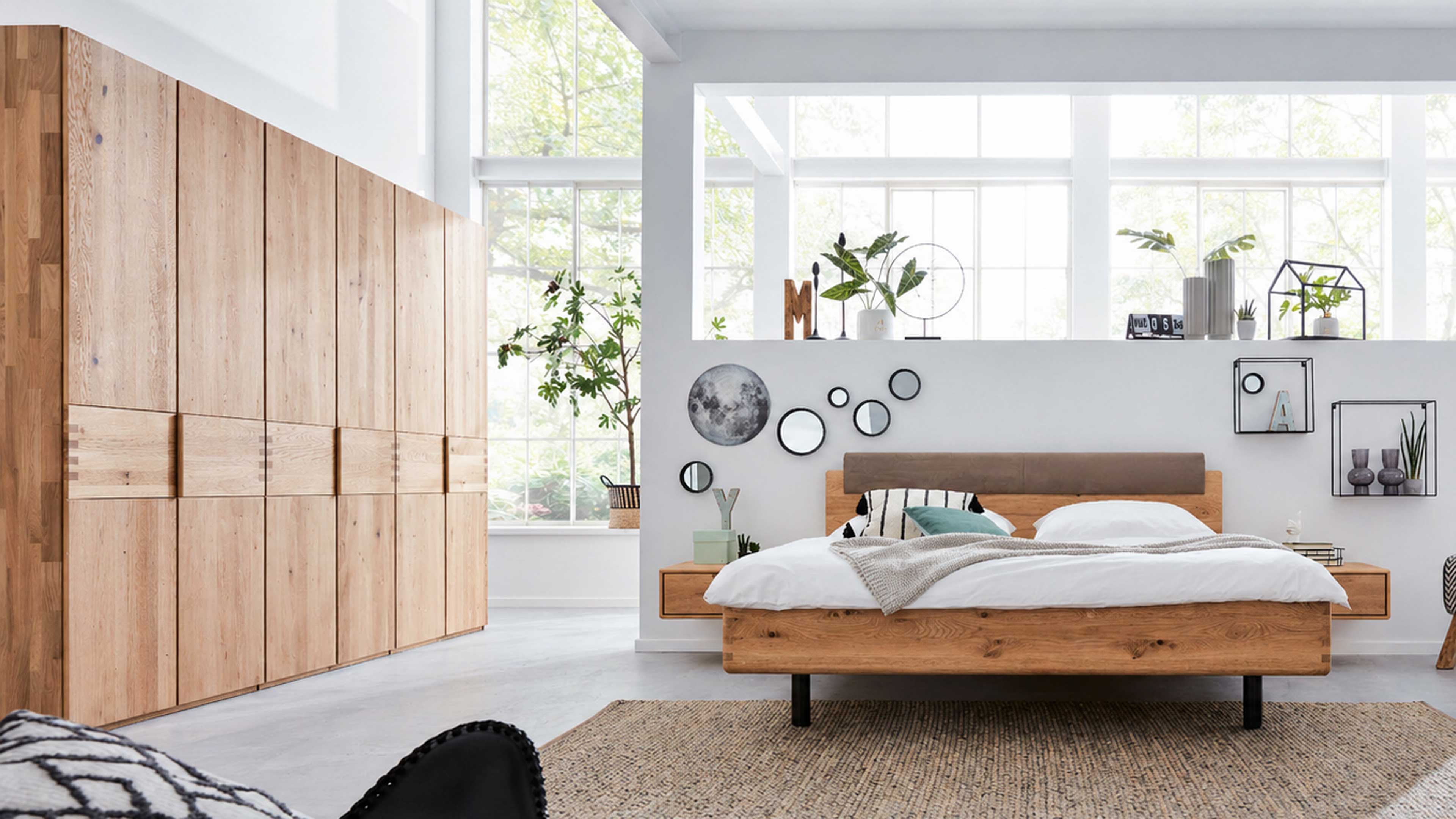 Doppelbett aus Holz mit gepolstertem Kopfteil, kombiniert mit großem Kleiderschrank und Nachttischen für ein abgestimmtes Schlafzimmer