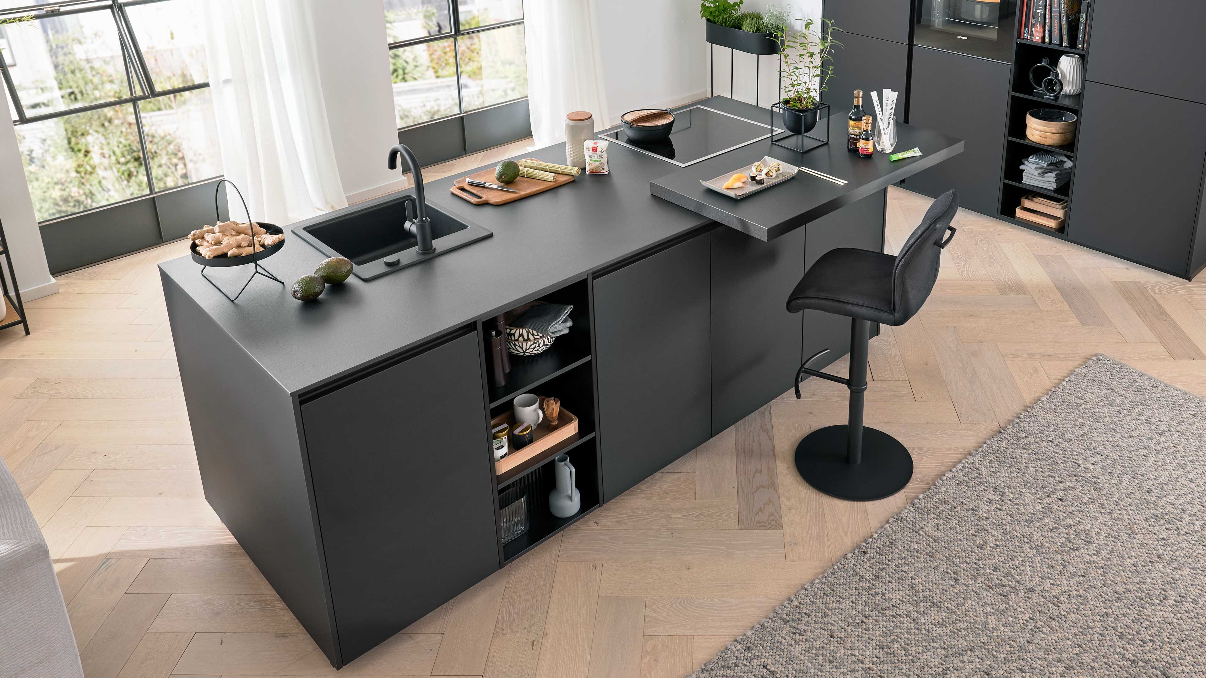 Schwarze Kücheninsel mit eingelassenem Spülbecken und Armatur, Kochfeld, offenen Regalfächern und Barhocker.