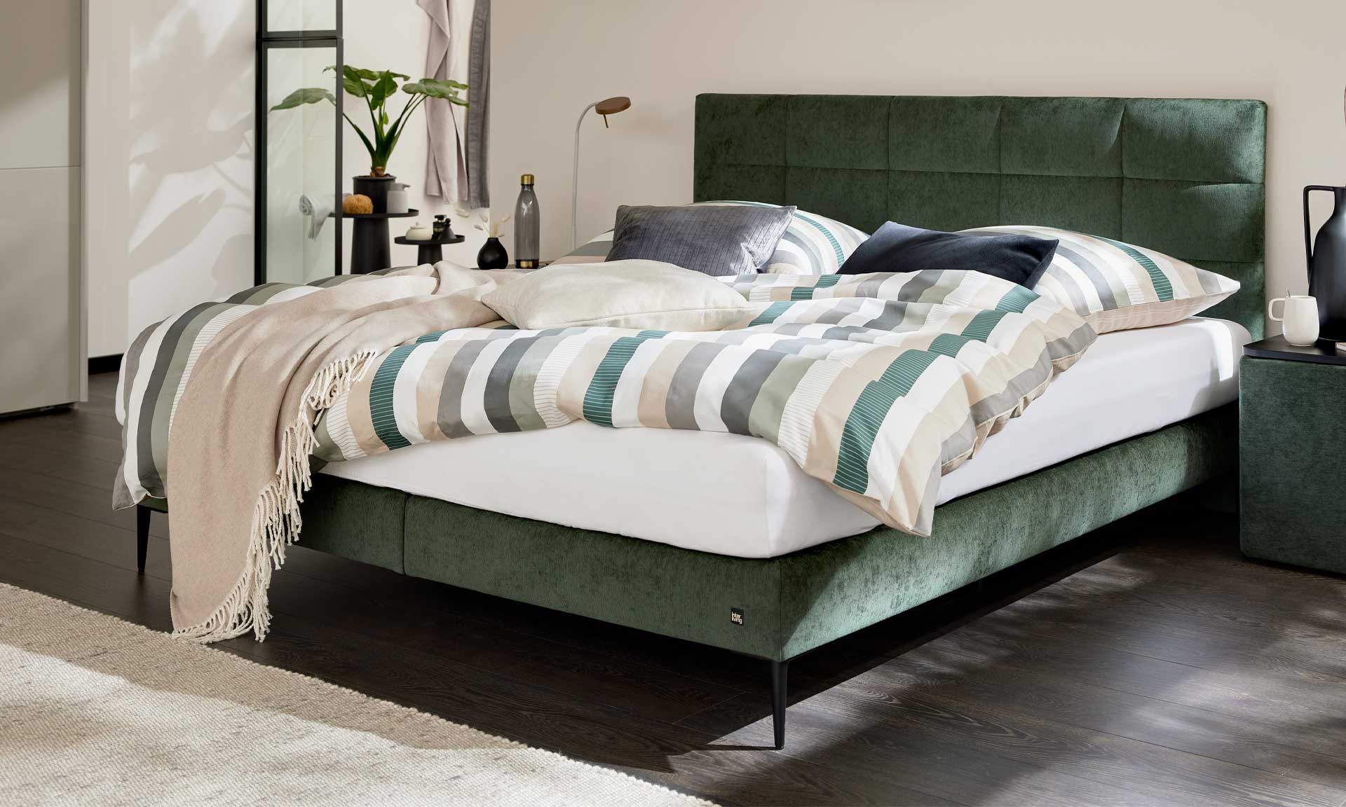 Boxspringbett mit moosgrünem Bezug und schwarzen Metallfüßen