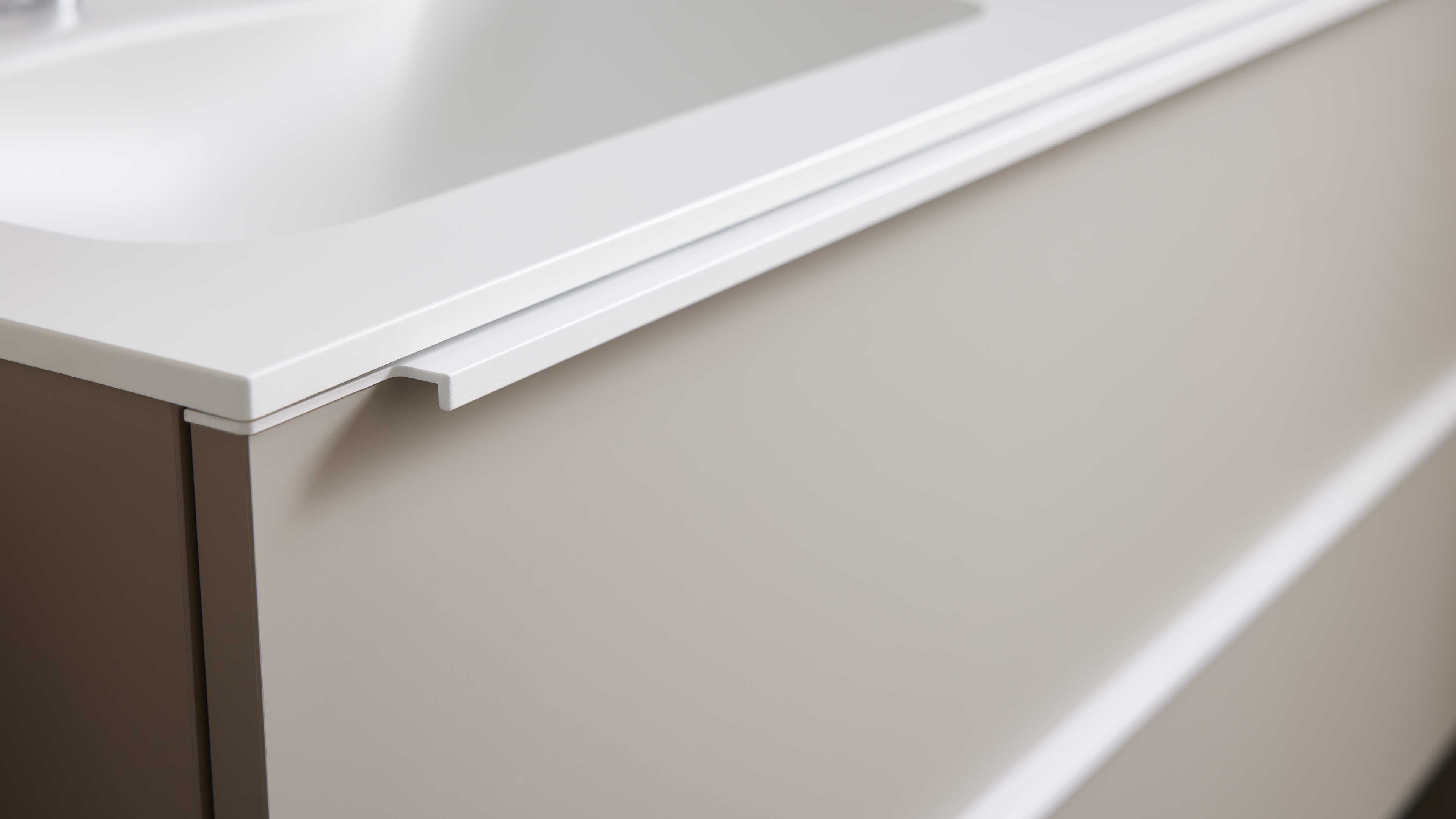 Front einer beigen Waschtischunterschrank-Schublade mit weißer Arbeitsplatte und integriertem Griffprofil.