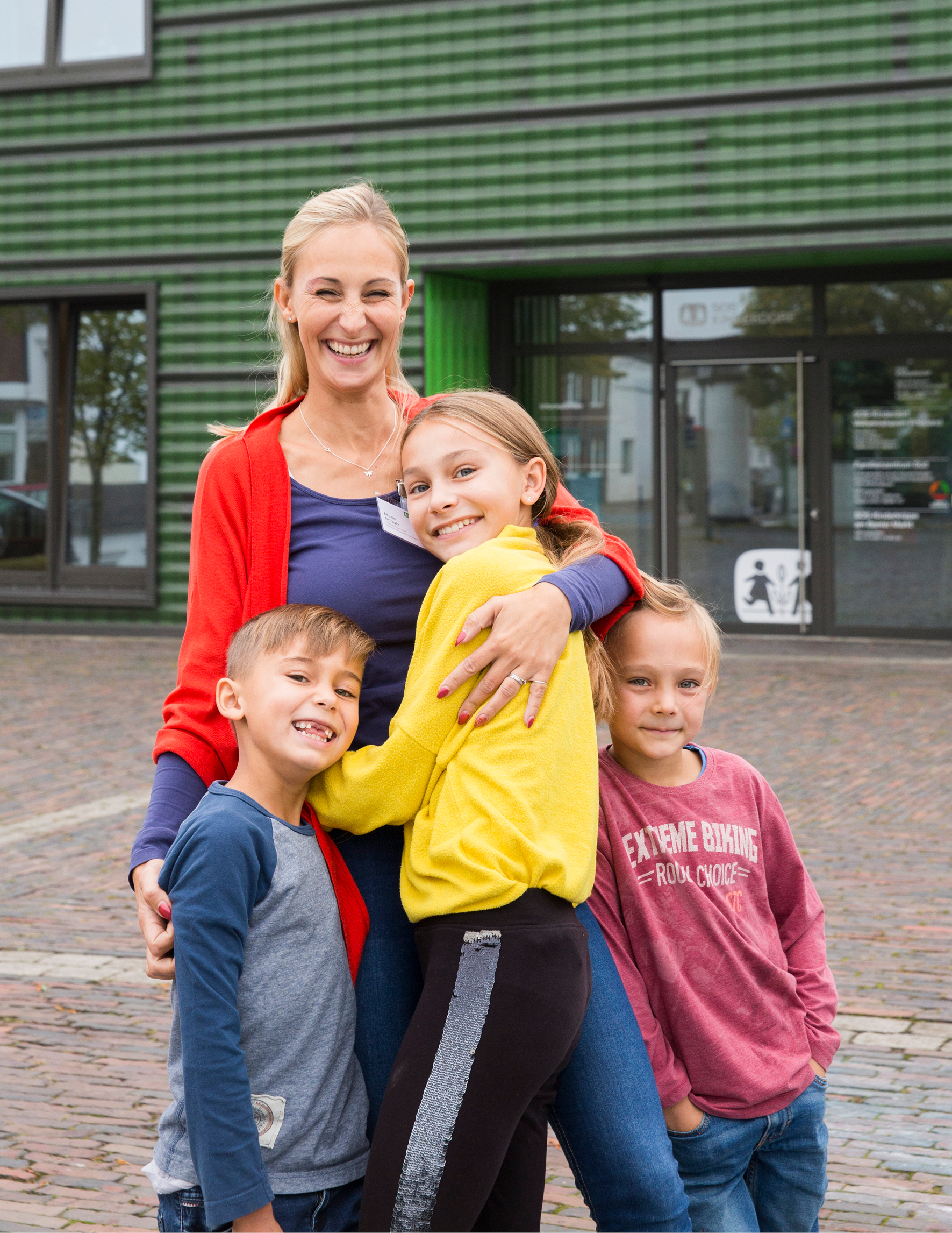 Kinder umarmen eine Mitarbeiterin von SOS-Kinderdorf