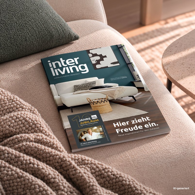 Das Interliving Wohnbuch Jubiläums-Edition 2026/2027 liegt auf einem Sofa.