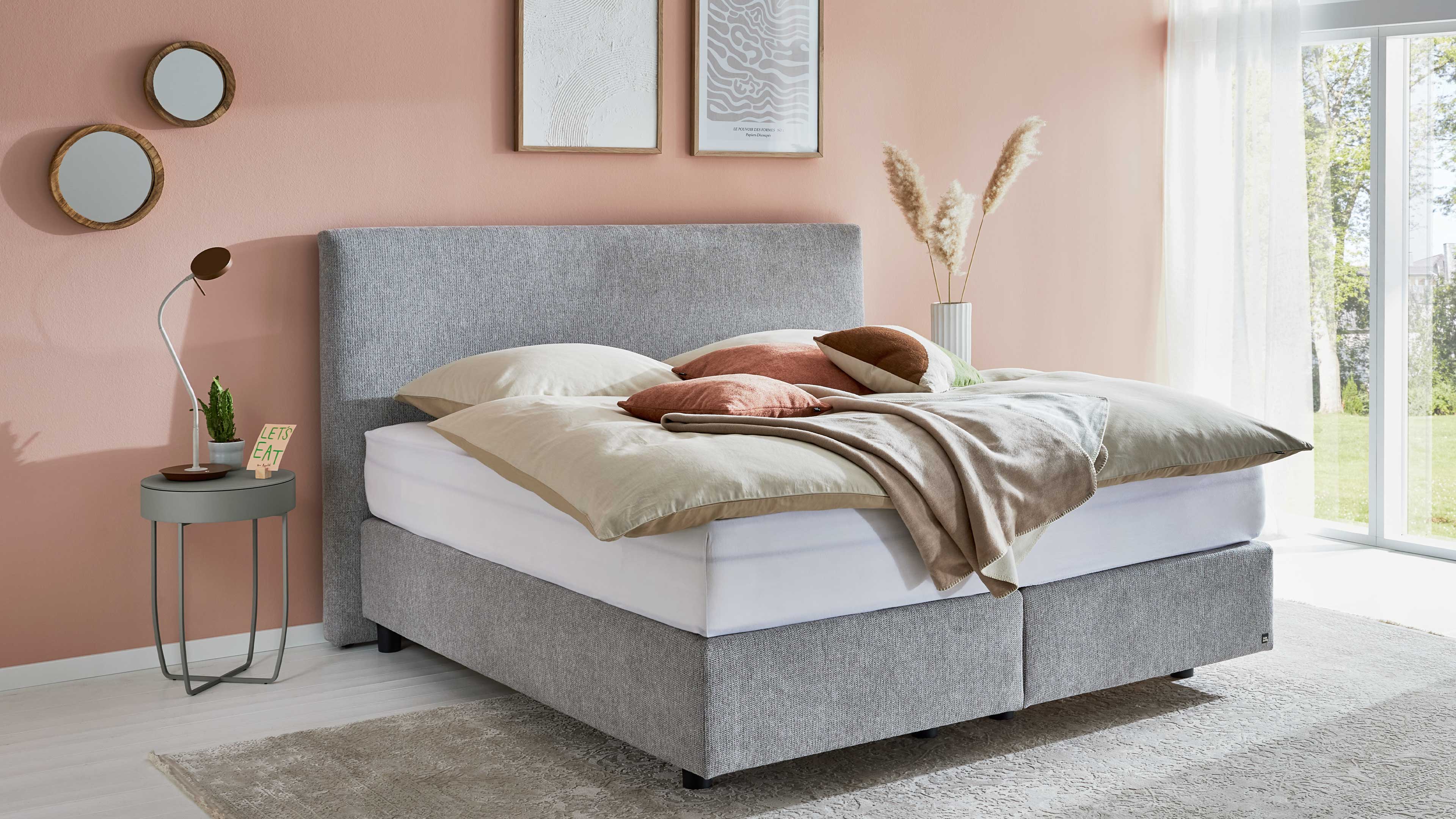 Modernes Polsterbett mit grauem Stoffbezug und durchgehender Matratze für ein harmonisches Schlafbild