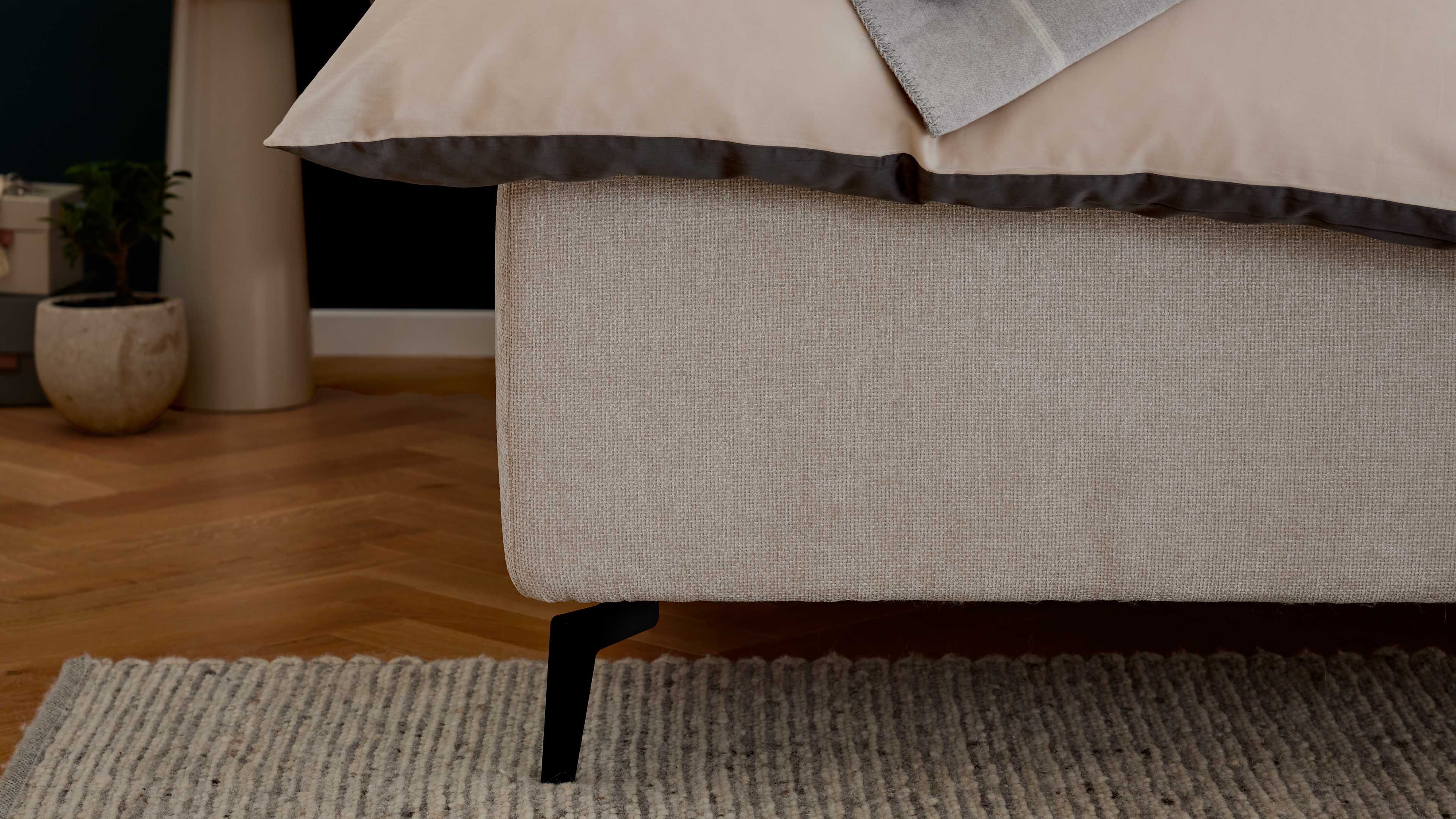 Elegantes Polsterbett in hellem Stoff mit gestepptem Kopfteil und filigranen Metallfüßen