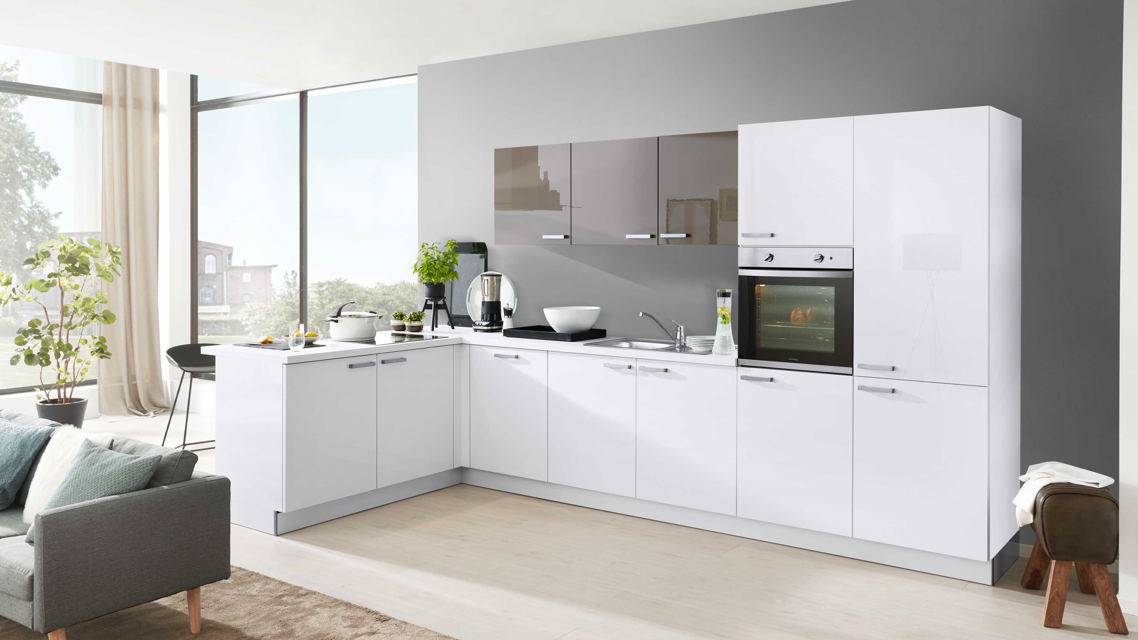 Ein L-förmiges, weiß-glänzendes Küchenzeilen-Set mit grauer Rückwand, integrierter Backofen, Spüle, Arbeitsplatte und Metallgriffen.