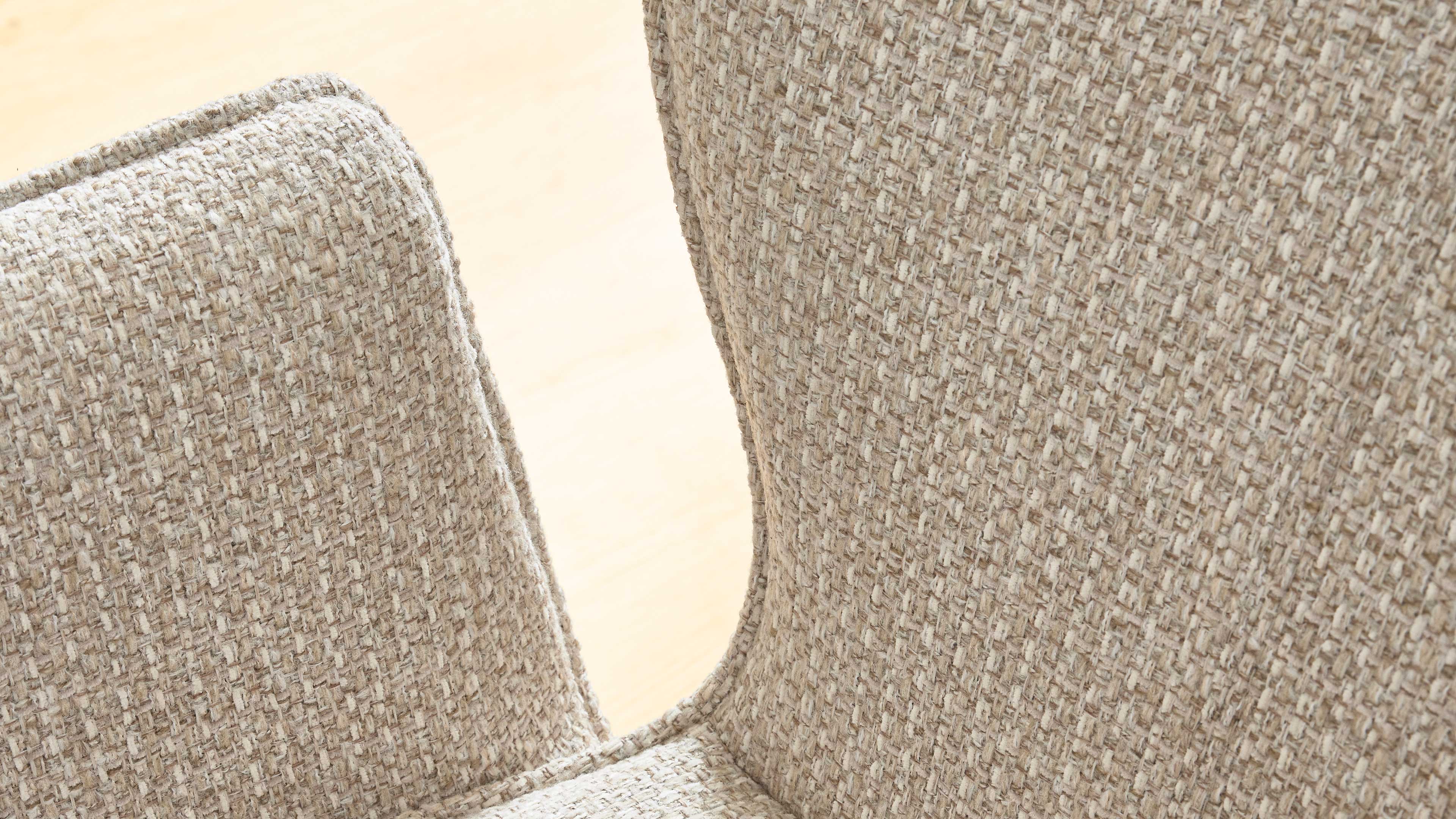 Sitzfläche und Rückenlehne eines Stuhls mit grob gewebtem beigen Stoff vor hellem Holzfußboden.