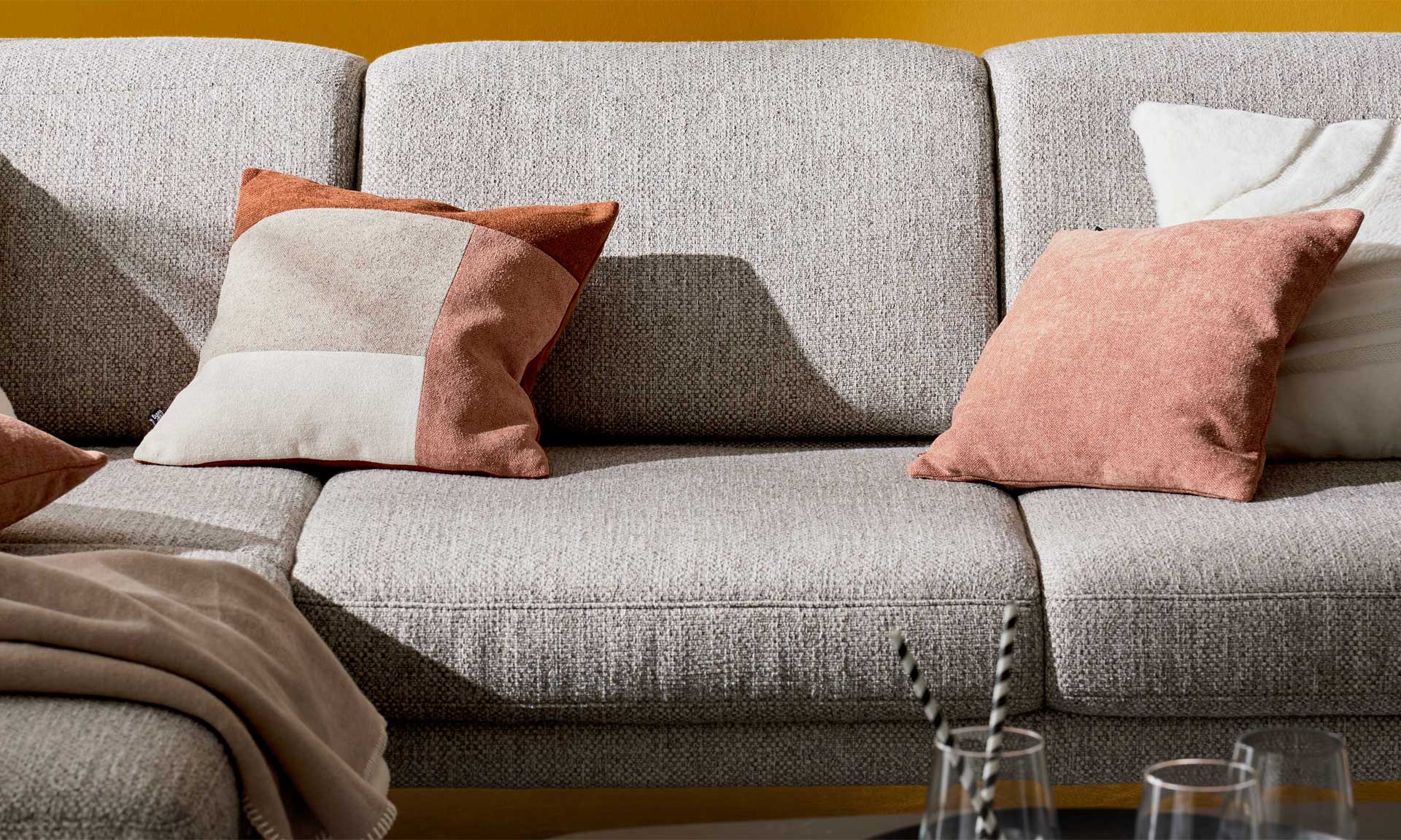 Ecksofa mit runden schwarzen Metallfüßen und Stoff in Silber