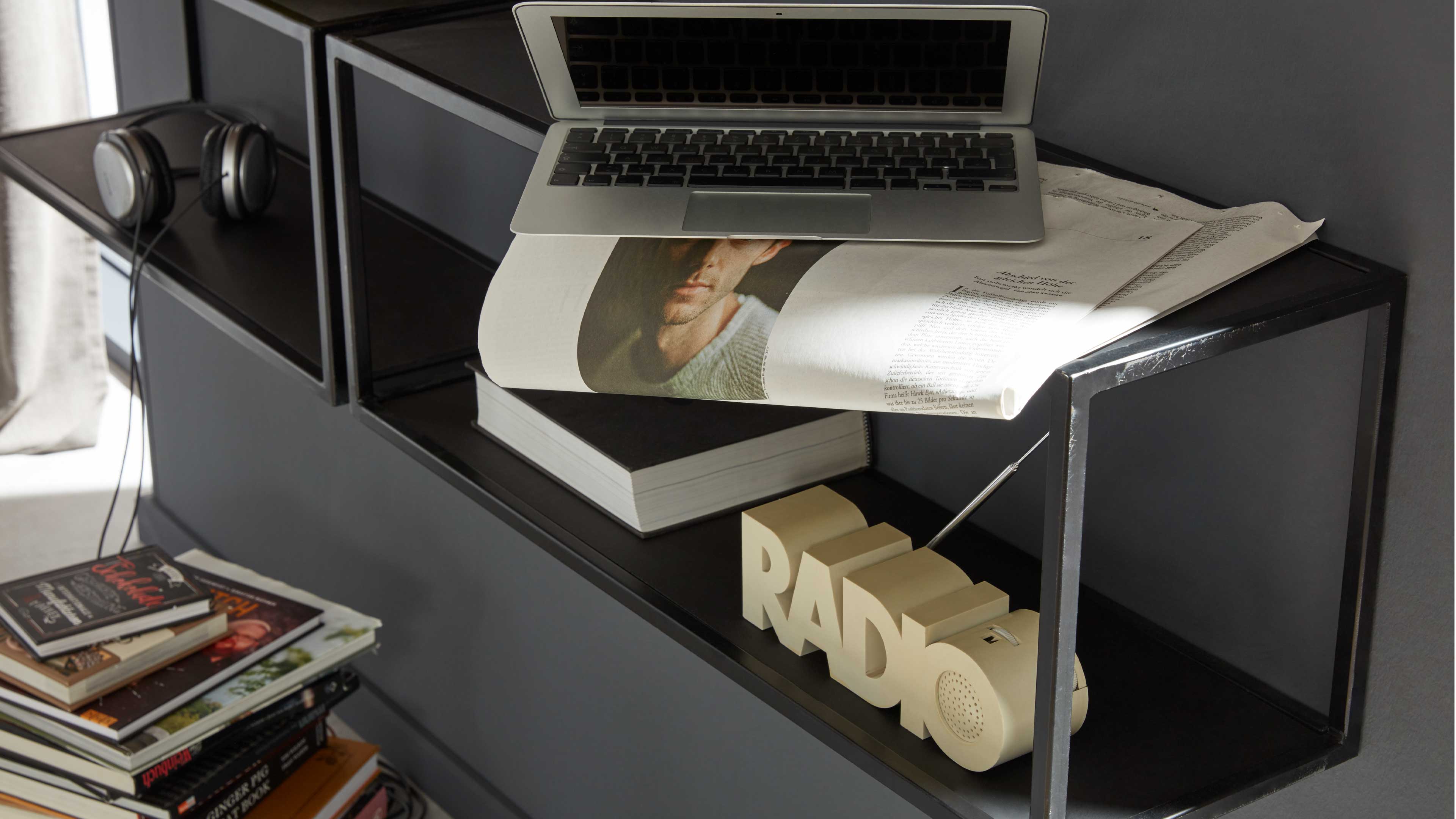 Wandregal aus offenem rechteckigem Metallrahmen mit dunklen, dünnen Ablageflächen in matter schwarzer Optik.