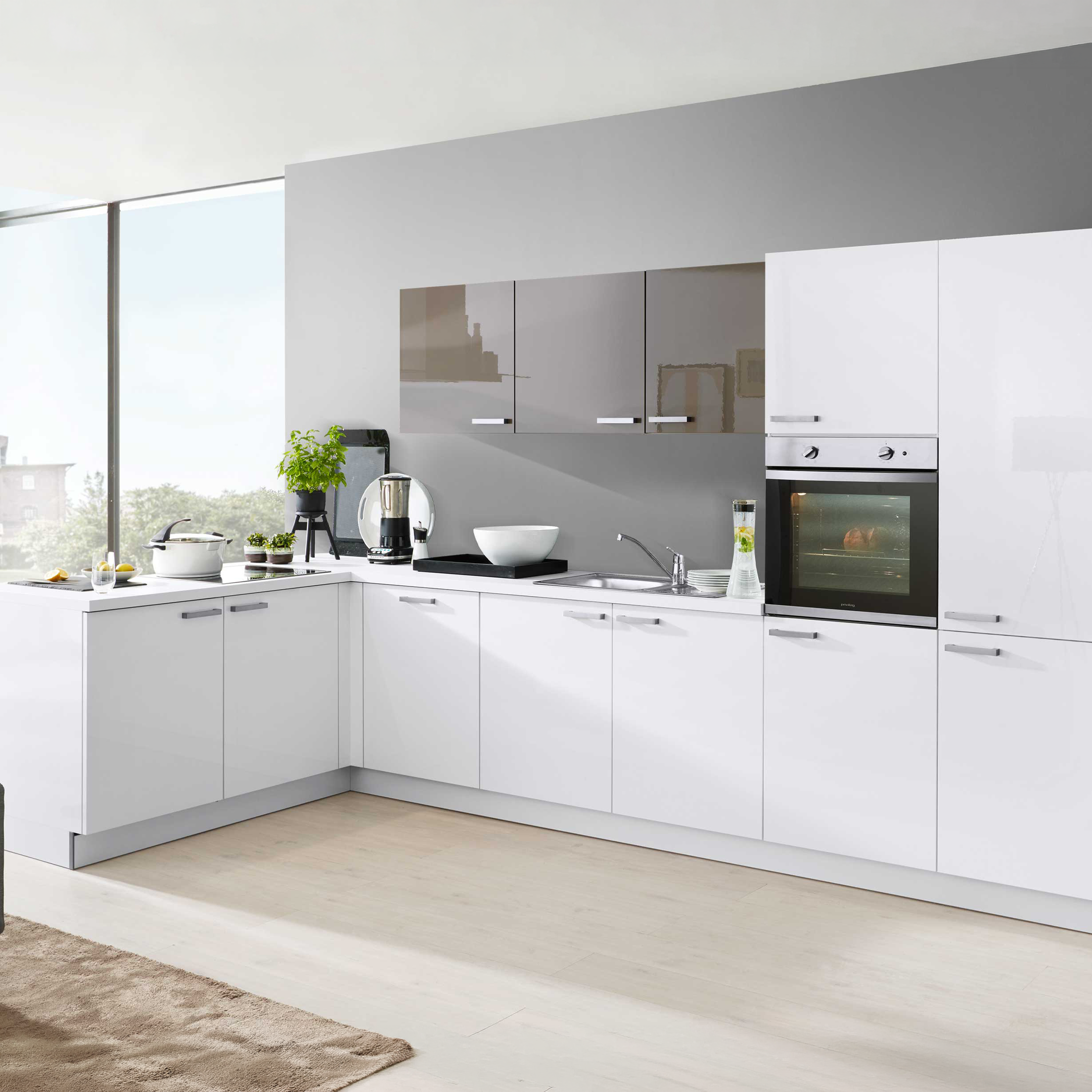 Ein L-förmiges, weiß-glänzendes Küchenzeilen-Set mit grauer Rückwand, integrierter Backofen, Spüle, Arbeitsplatte und Metallgriffen.