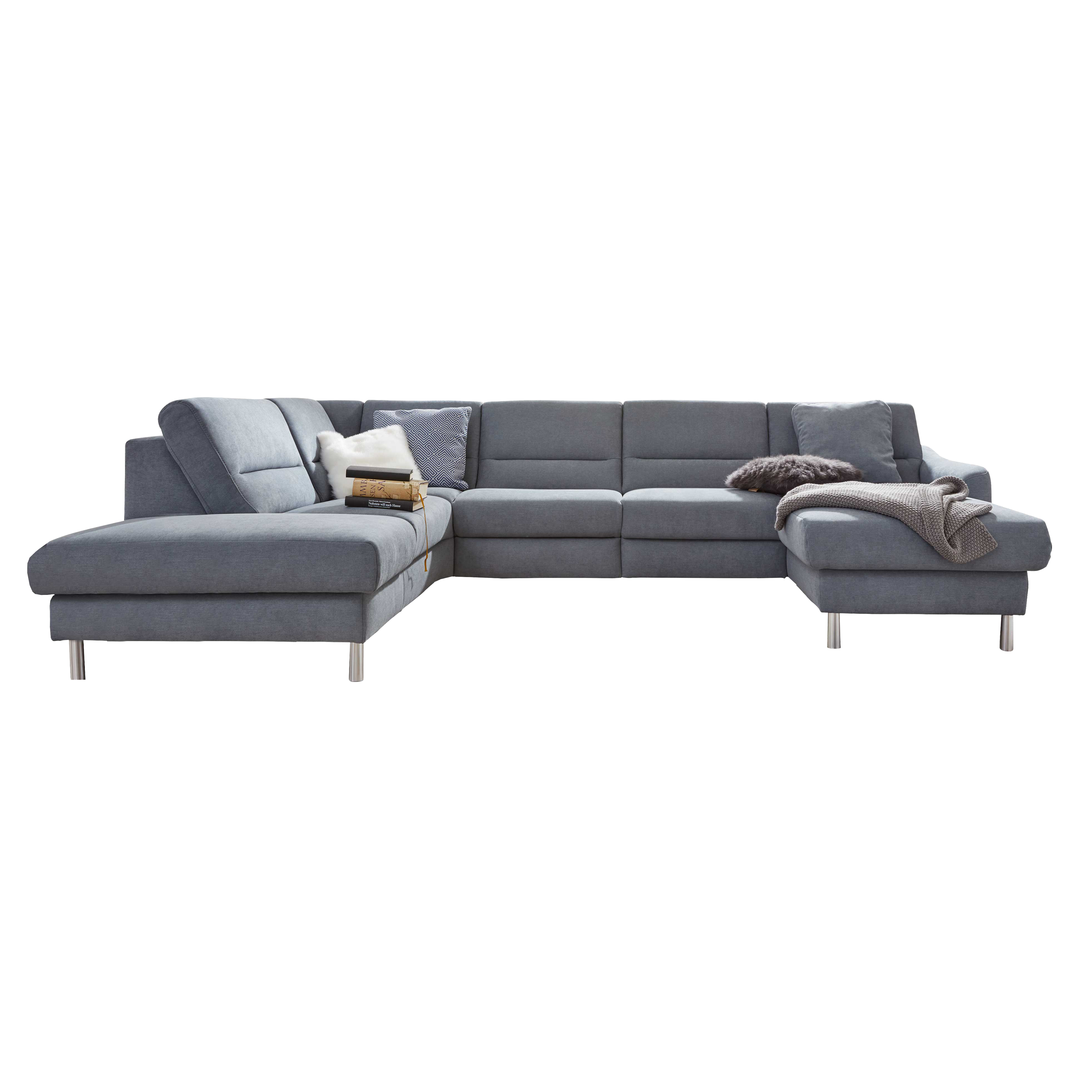 Große grau bezogene Eckcouch mit Metallfüßen, links längere Chaiselongue, rechts kürzerer Ottomane, Kissen, Decke und Bücher.