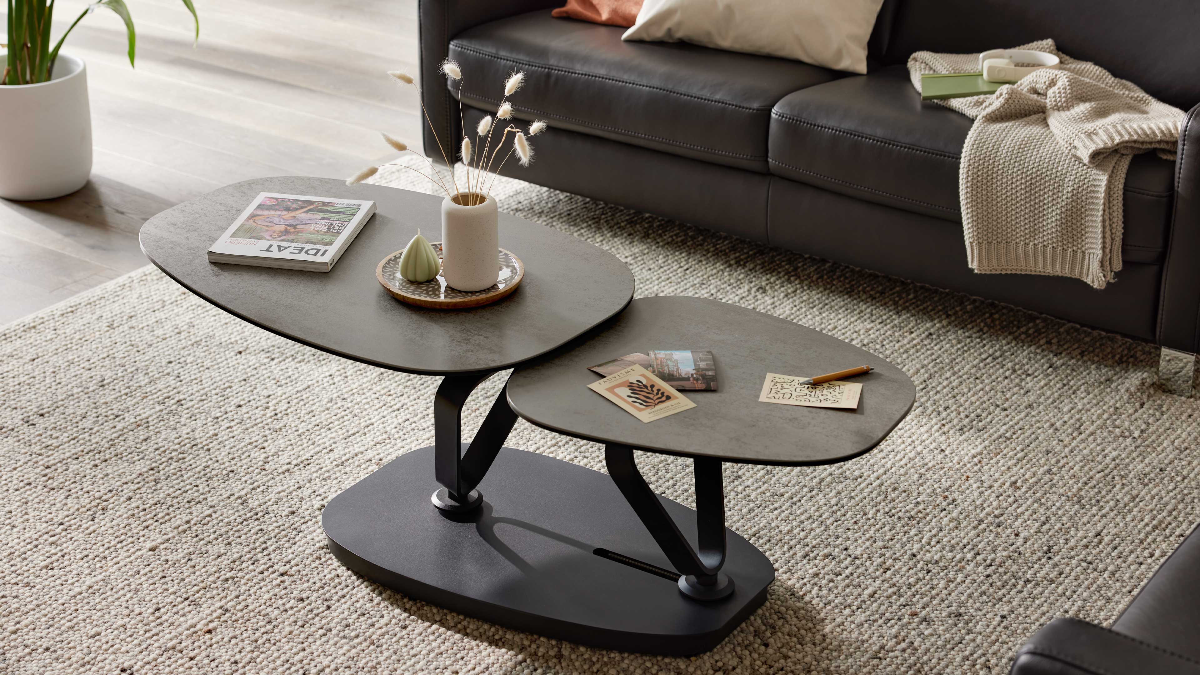 Grauer Couchtisch mit drehbarer Keramikplatte und schwarzem Sockel