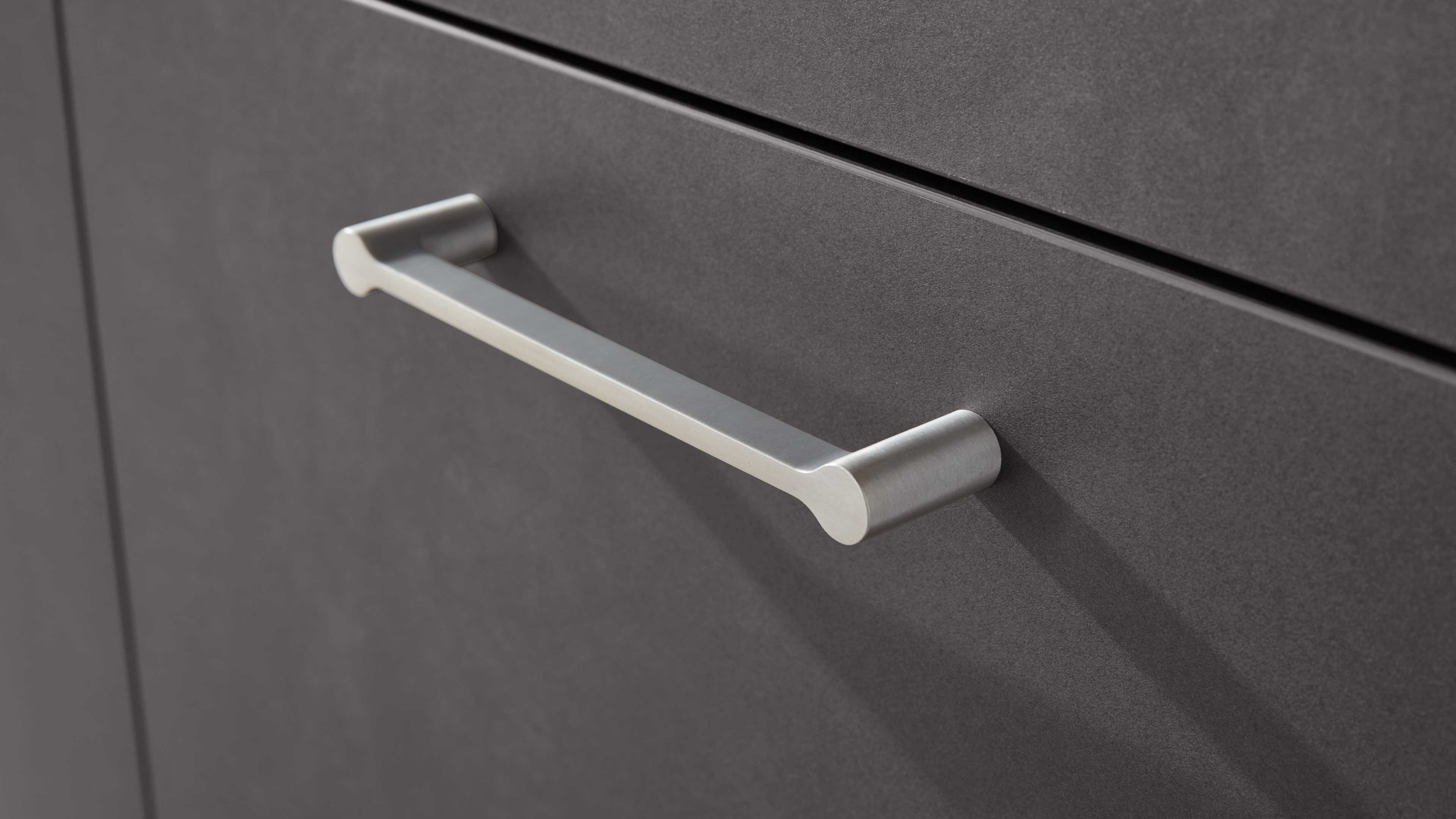 Schubladengriff: horizontale Griffstange aus gebürstetem Metall mit zylindrischen, runden Enden an dunkelgrauer matter Front.