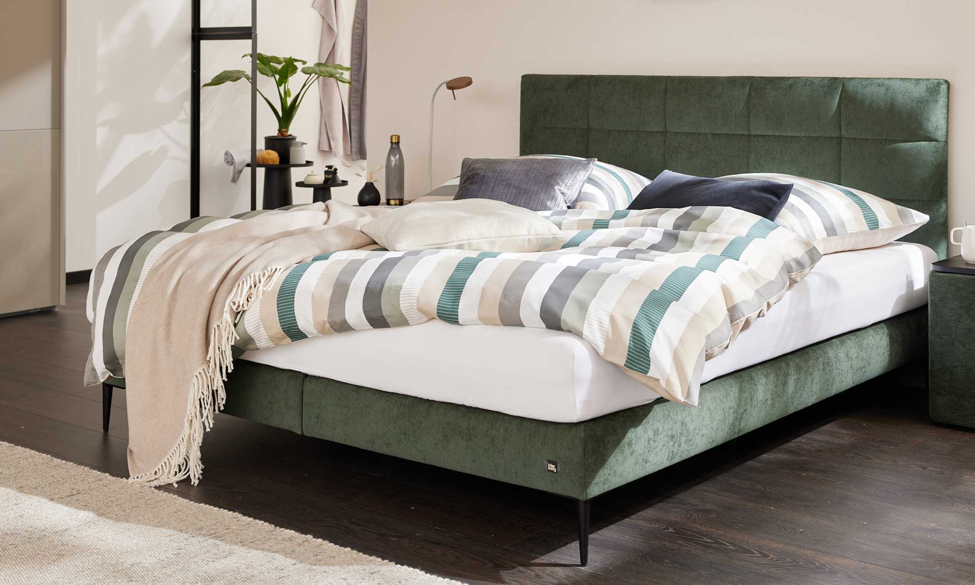 Boxspringbett mit moosgrünem Bezug und schwarzen Metallfüßen