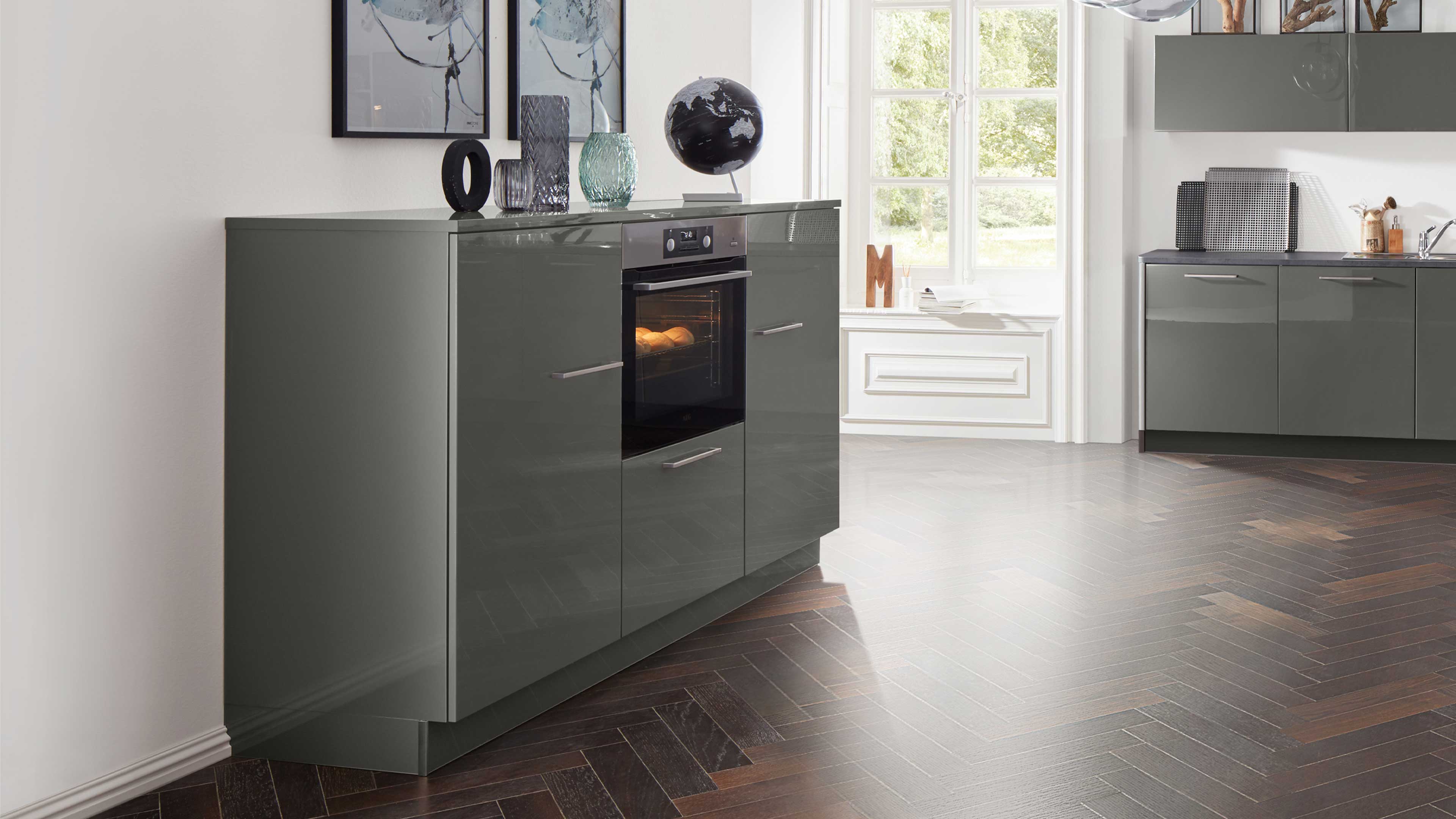 Freistehender Küchenunterschrank in hochglänzendem Grauton mit drei Fronten, Metallgriffen und eingebautem Ofen mit Sichtfenster.