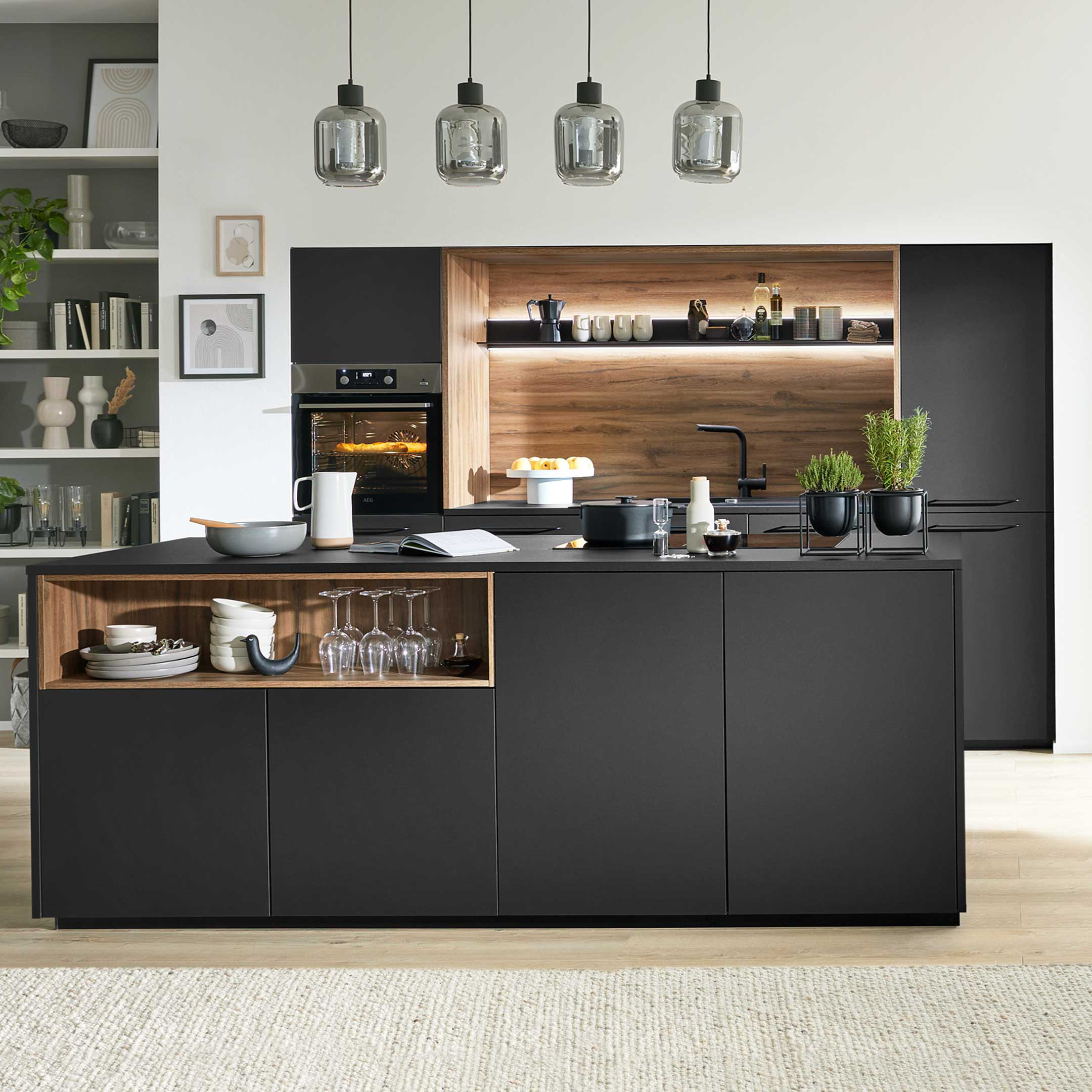 Schwarze Kücheninsel mit offenem Holzfach, eingebautem Backofen und Holzrückwand, hängenden Glaslampen und seitlichem Sideboard.