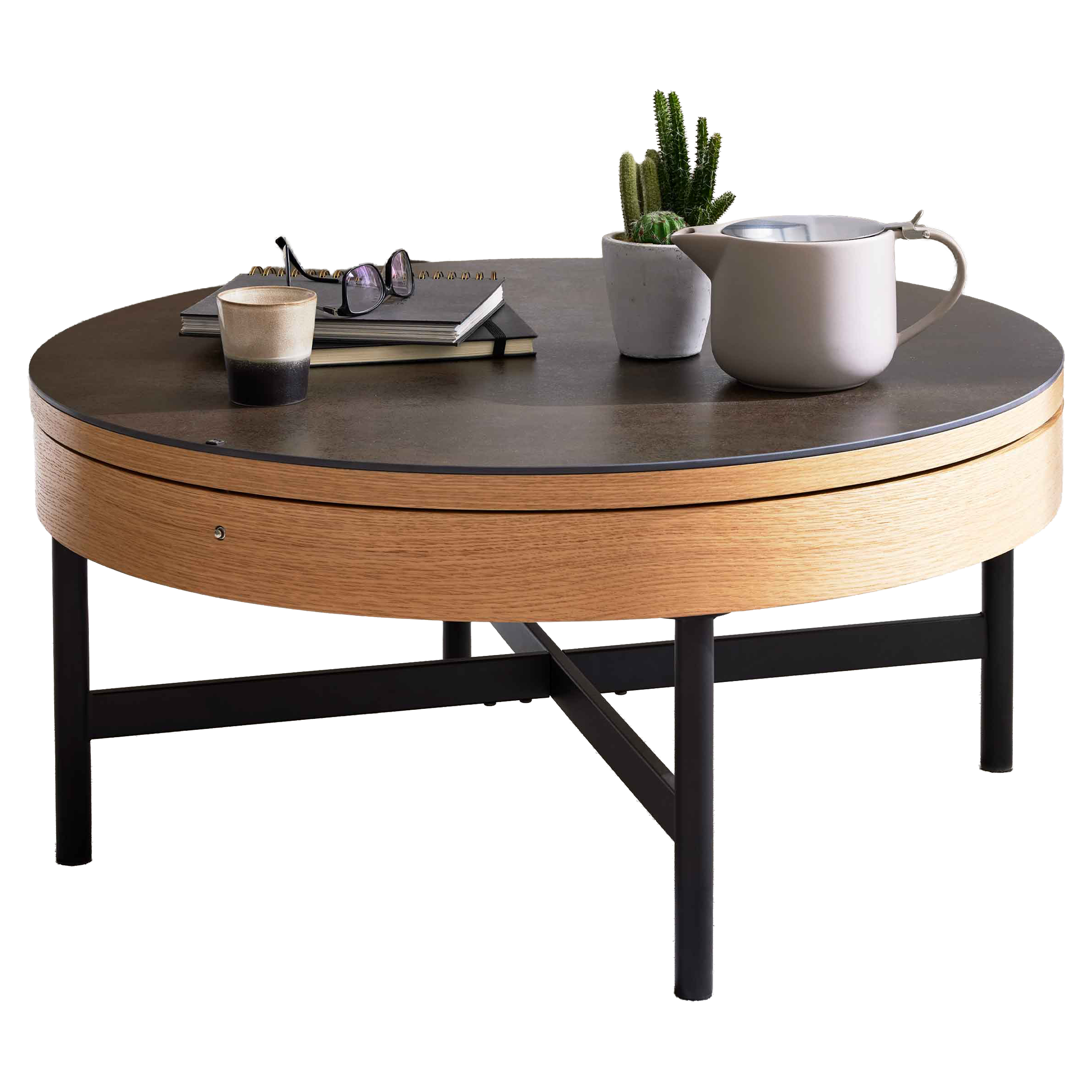 Runder Couchtisch mit dunkler Platte, Holzrand und schwarzen Beinen, mit Kaktus, Kanne, Brille und Tasse, hinter ihm ein grünes Sofa.