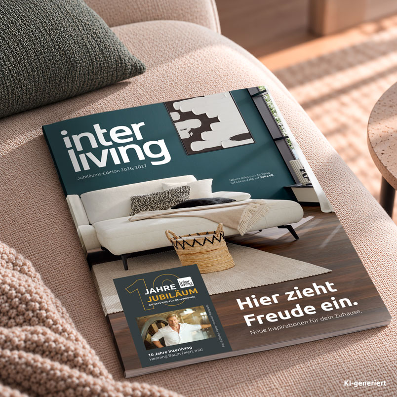 Das Interliving Wohnbuch Jubiläums-Edition 2026/2027 liegt auf einem Sofa.