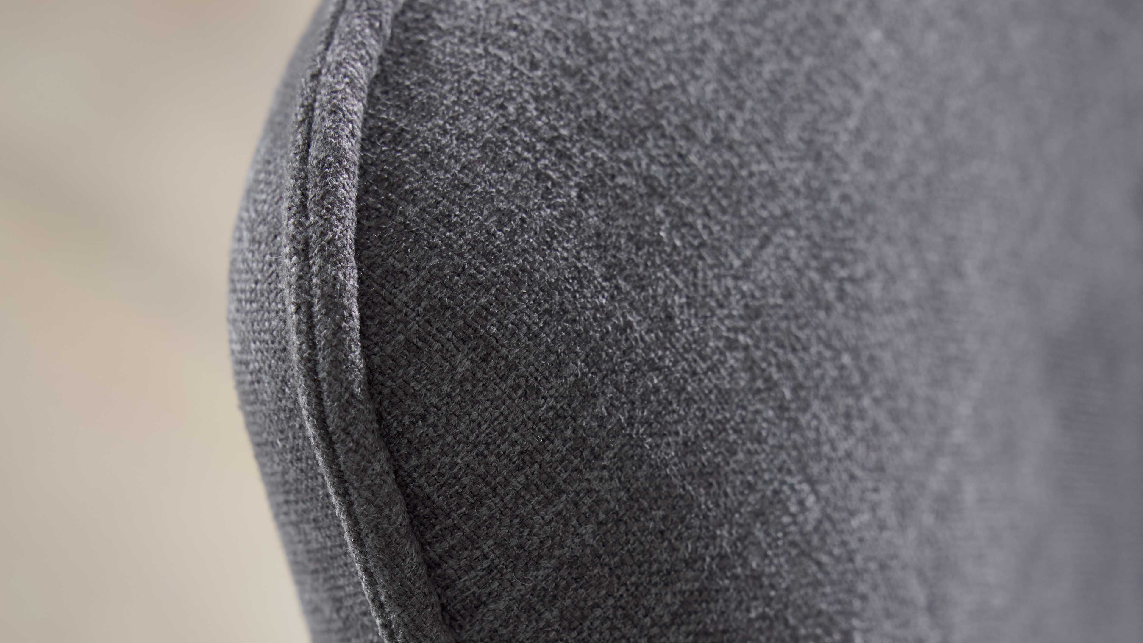 Nahaufnahme einer grauen Polsterfläche mit rundem Rand und sichtbarer Ziernaht, feine textile Struktur erkennbar.