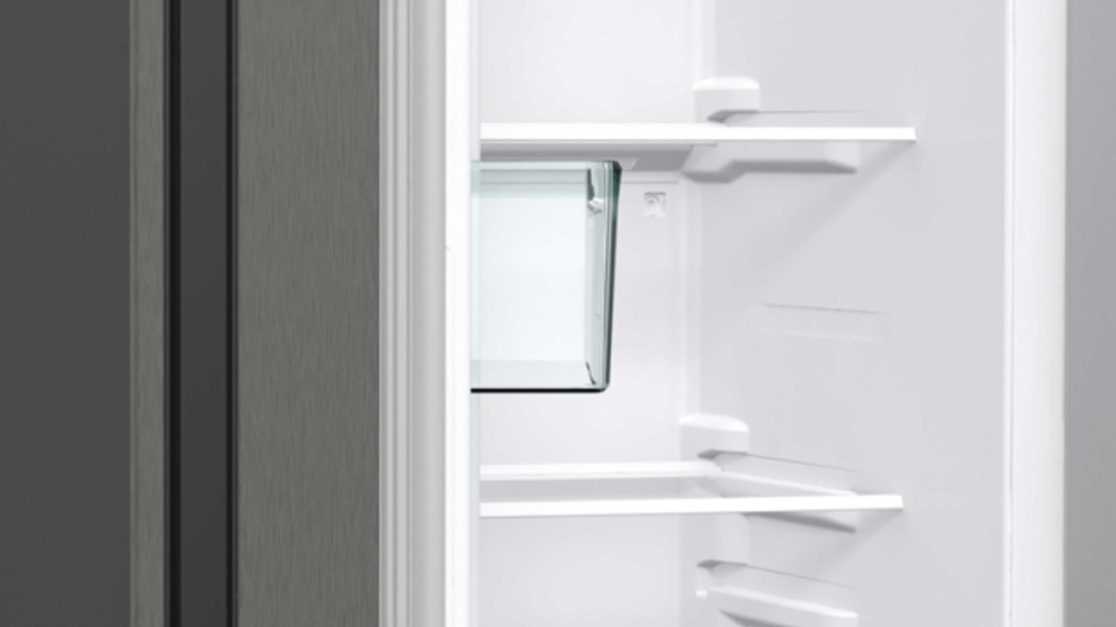 Geöffneter Kühlschrank mit weißem Innenraum, zwei Glasablagen und einer teilweise sichtbaren transparenten Schublade.