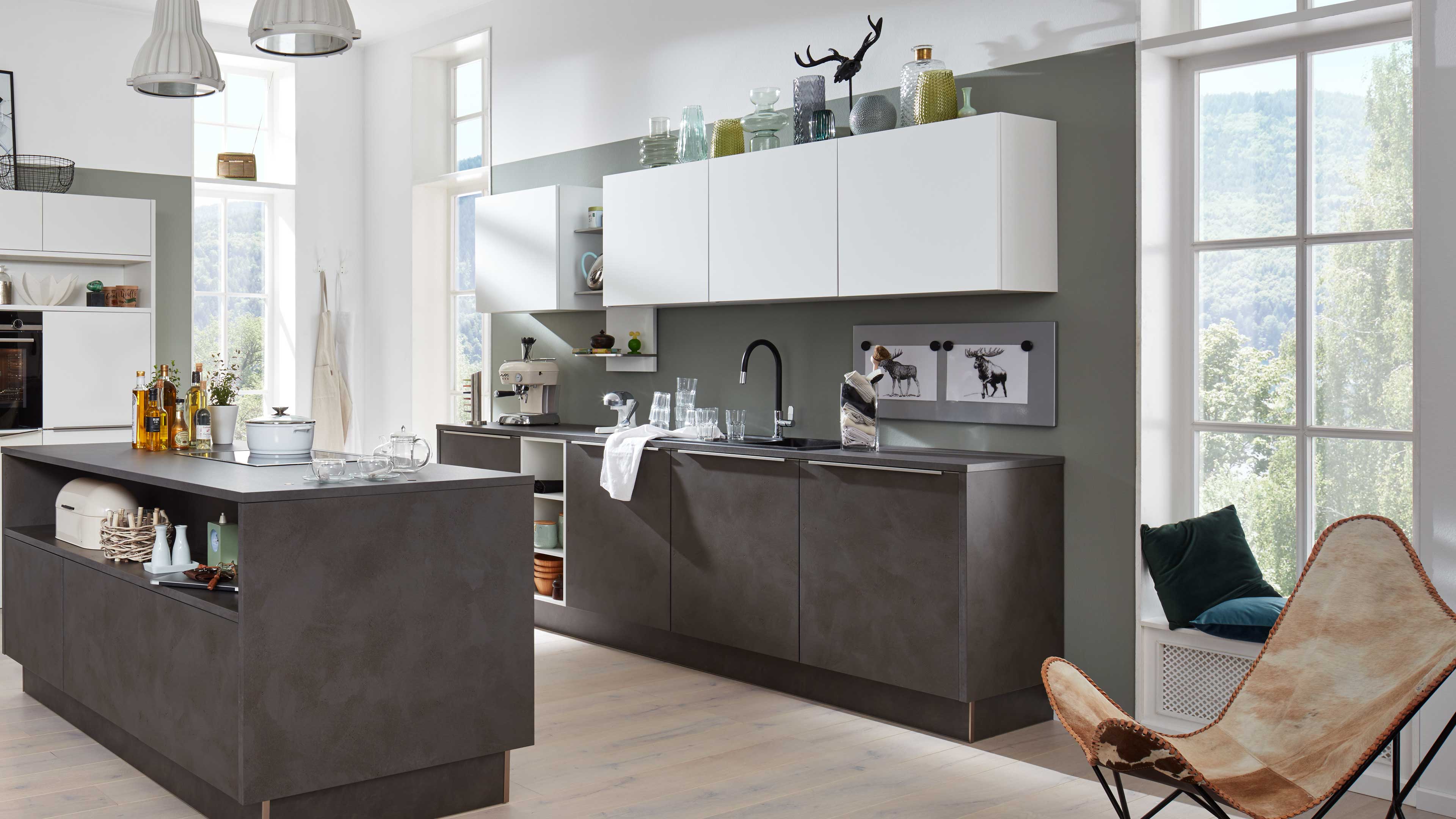 Moderne Küchenzeile mit dunkler, betonähnlich wirkender Unterschrankinsel und weißen, wandhängenden Oberschränken, schwarzer Armatur.