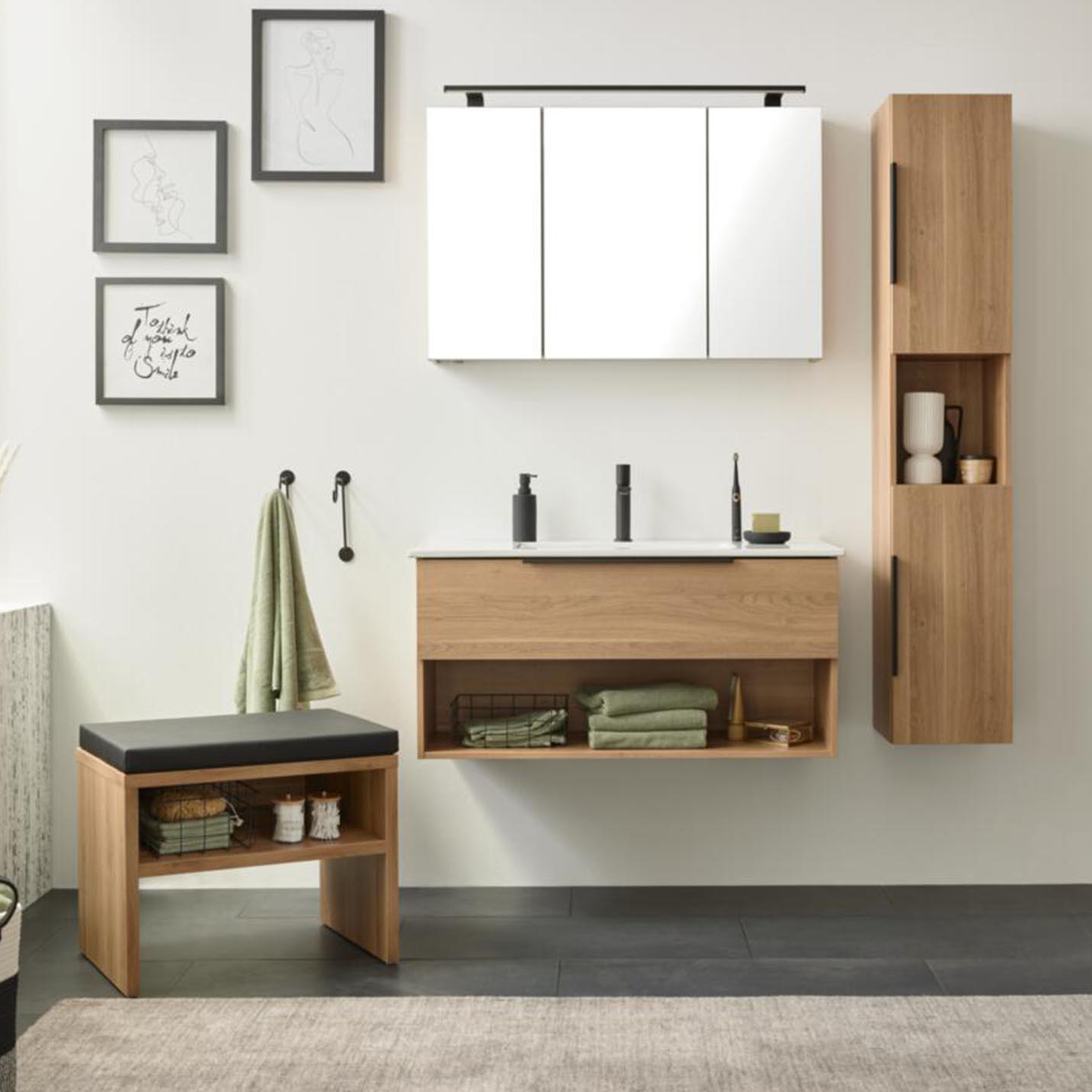 Schwebender Holz-Waschtisch mit weißer Ablage, darüber Spiegelschrank, offenes Fach mit Handtüchern und Hocker am Fenster.
