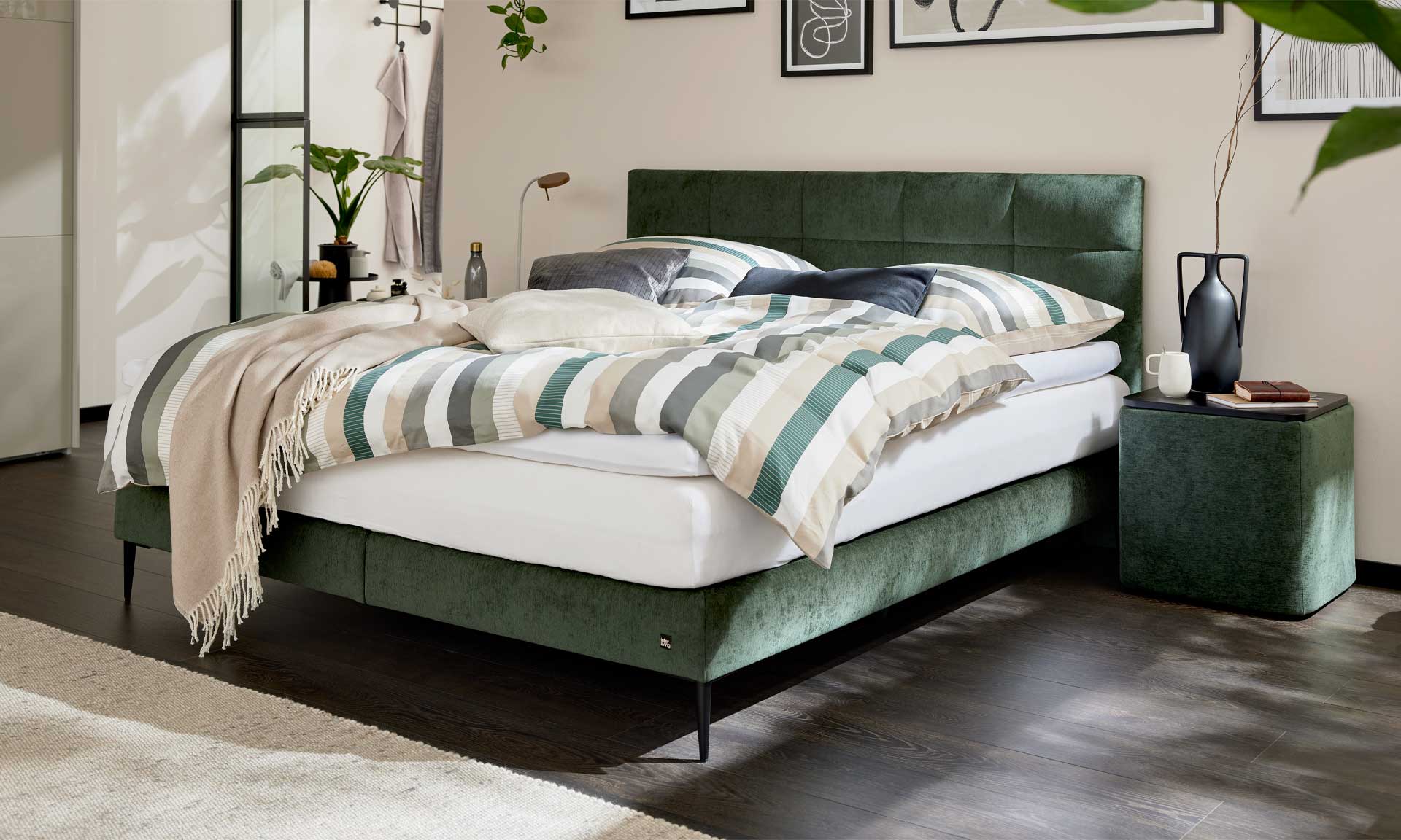 Boxspringbett mit moosgrünem Bezug und schwarzen Metallfüßen