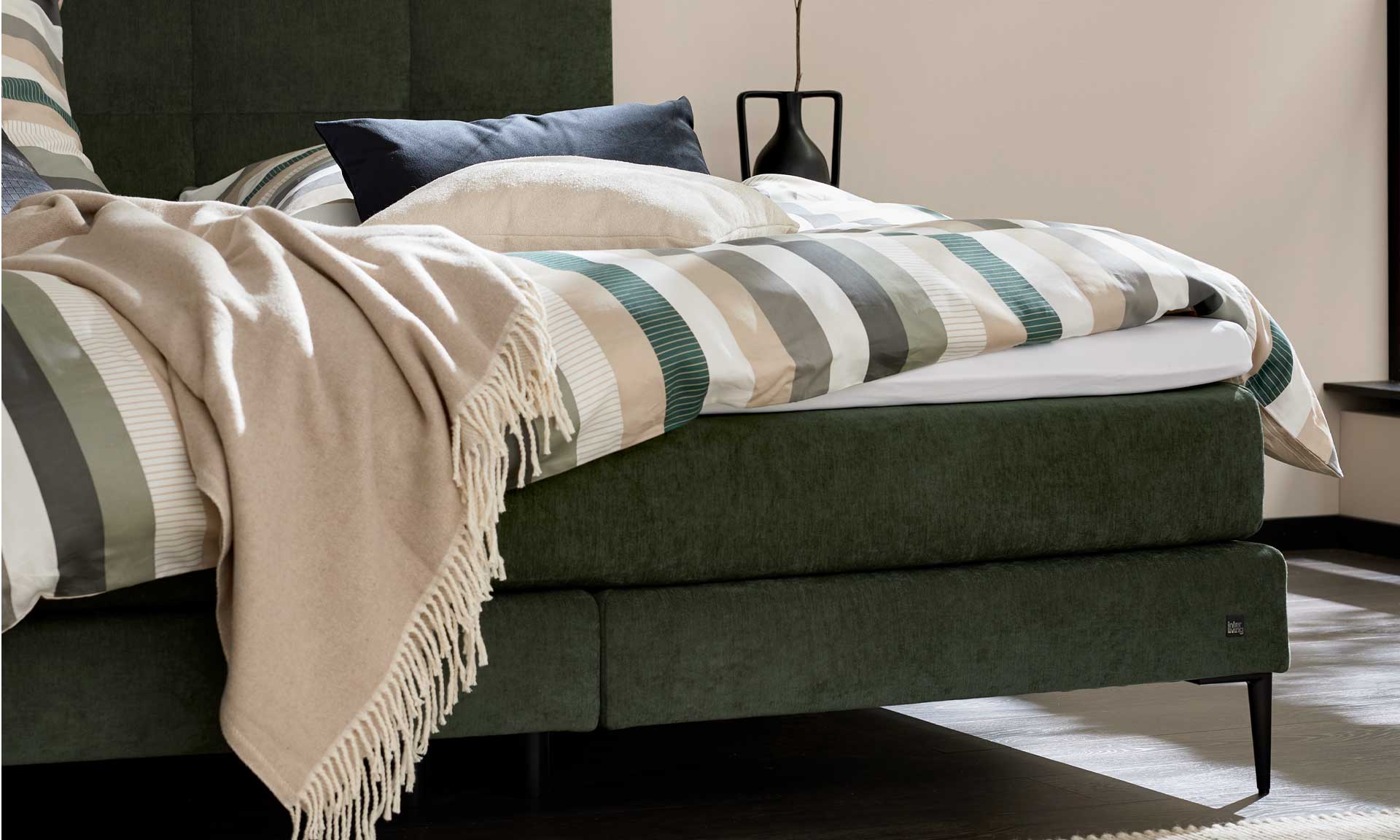 Moosgrünes Boxspringbett mit extra hohem Kopfteil und stoffbezogenen Matratzen