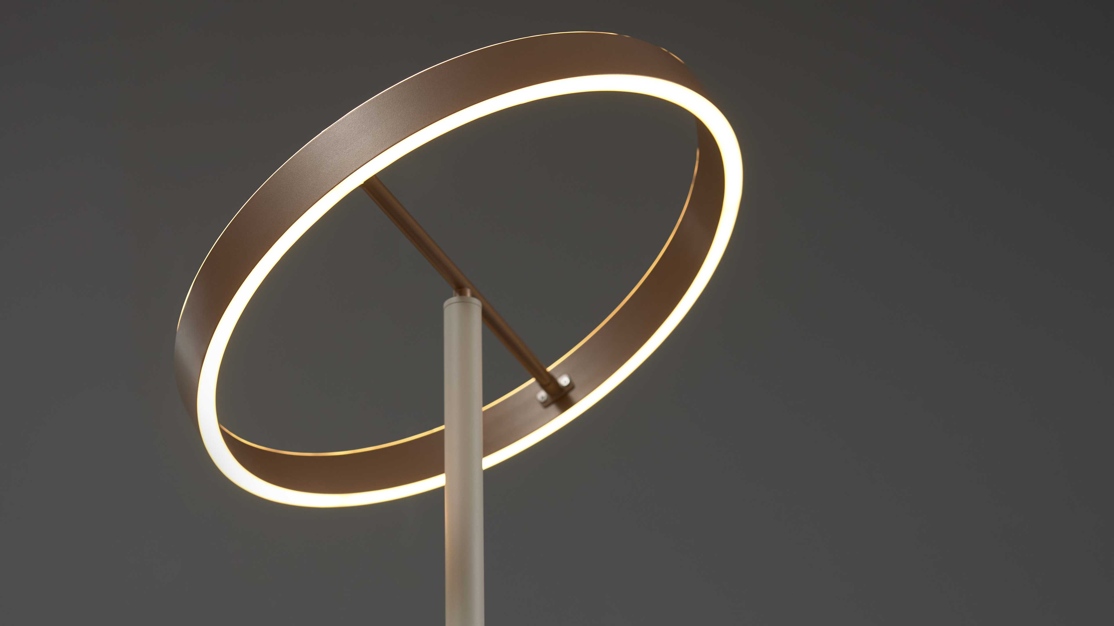 Runder Leuchtring mit warmweißem Leuchtband, an einem hellgrauen senkrechten Stab befestigt, diagonale Haltestange sichtbar.