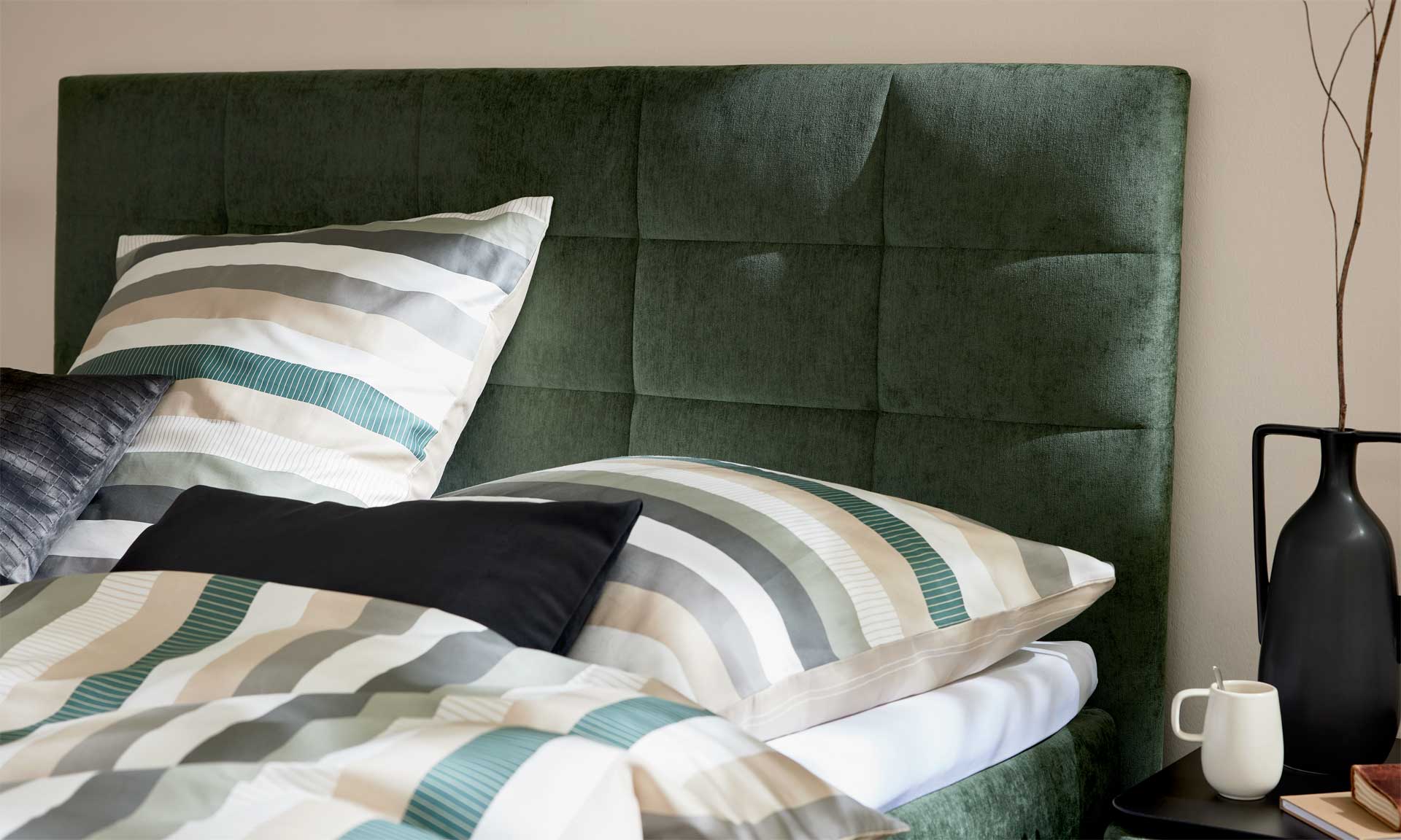 Moosgrünes Boxspringbett mit extra hohem Kopfteil und stoffbezogenen Matratzen