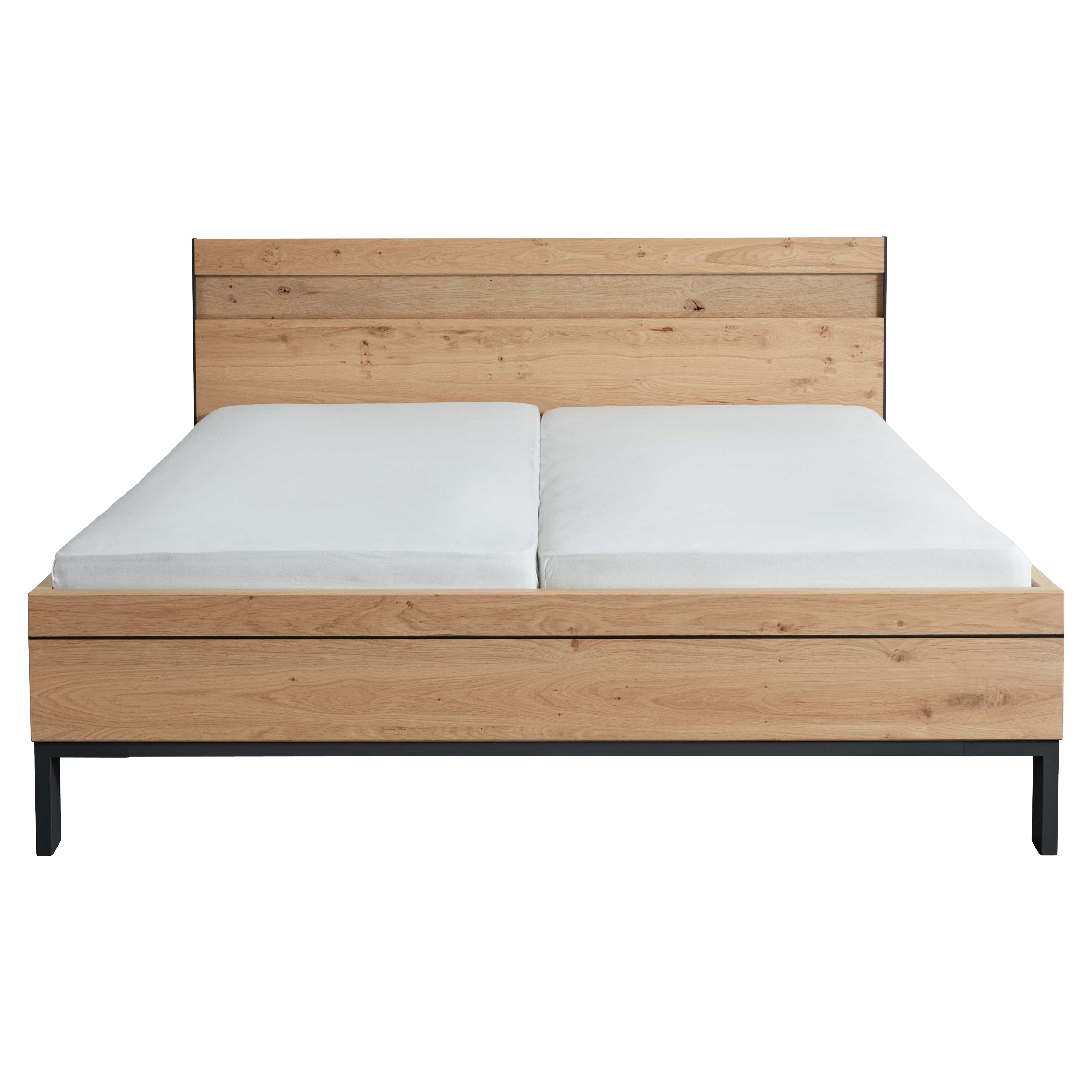 Bett mit hellen Holzplatten als Kopf- und Fußteil, geteilte weiße Matratzen und schwarzem Metallgestell mit Beinen.