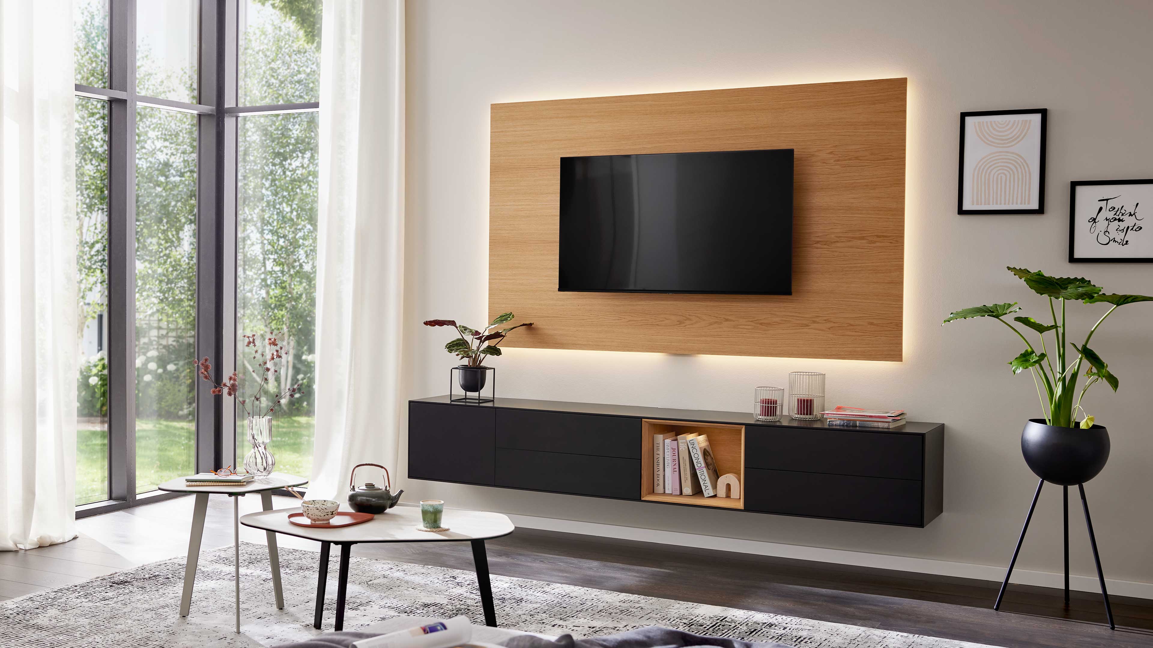 Schwarzes Lowboard mit Schubladen und offenem Holzfach ergänzt die TV-Wand mit praktischem Stauraum und klarer Linienführung