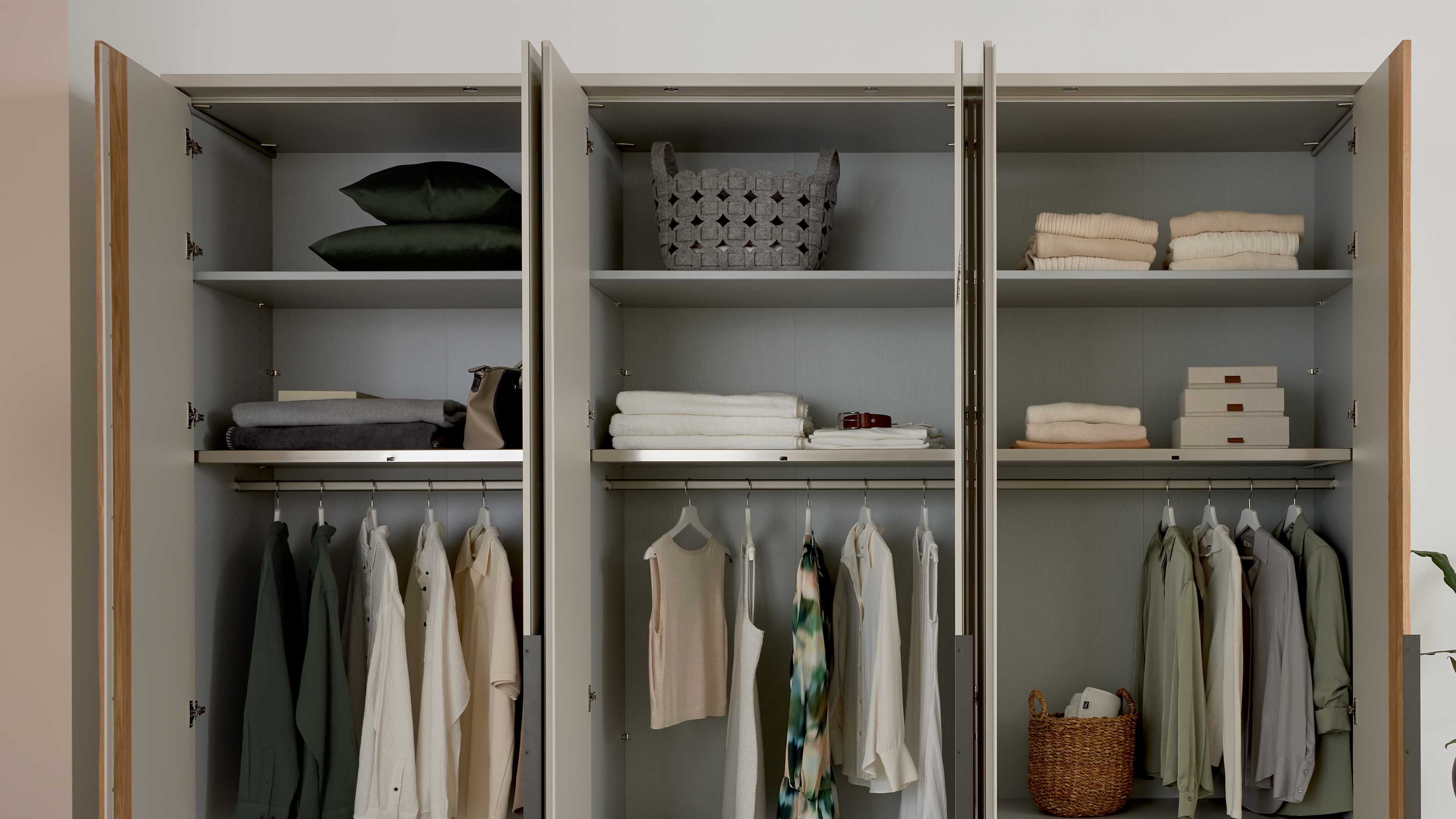Vierteiliges Schlafzimmer mit Bett, Nachtkonsolen und großem Kleiderschrank in hellem Grau mit Holzakzenten