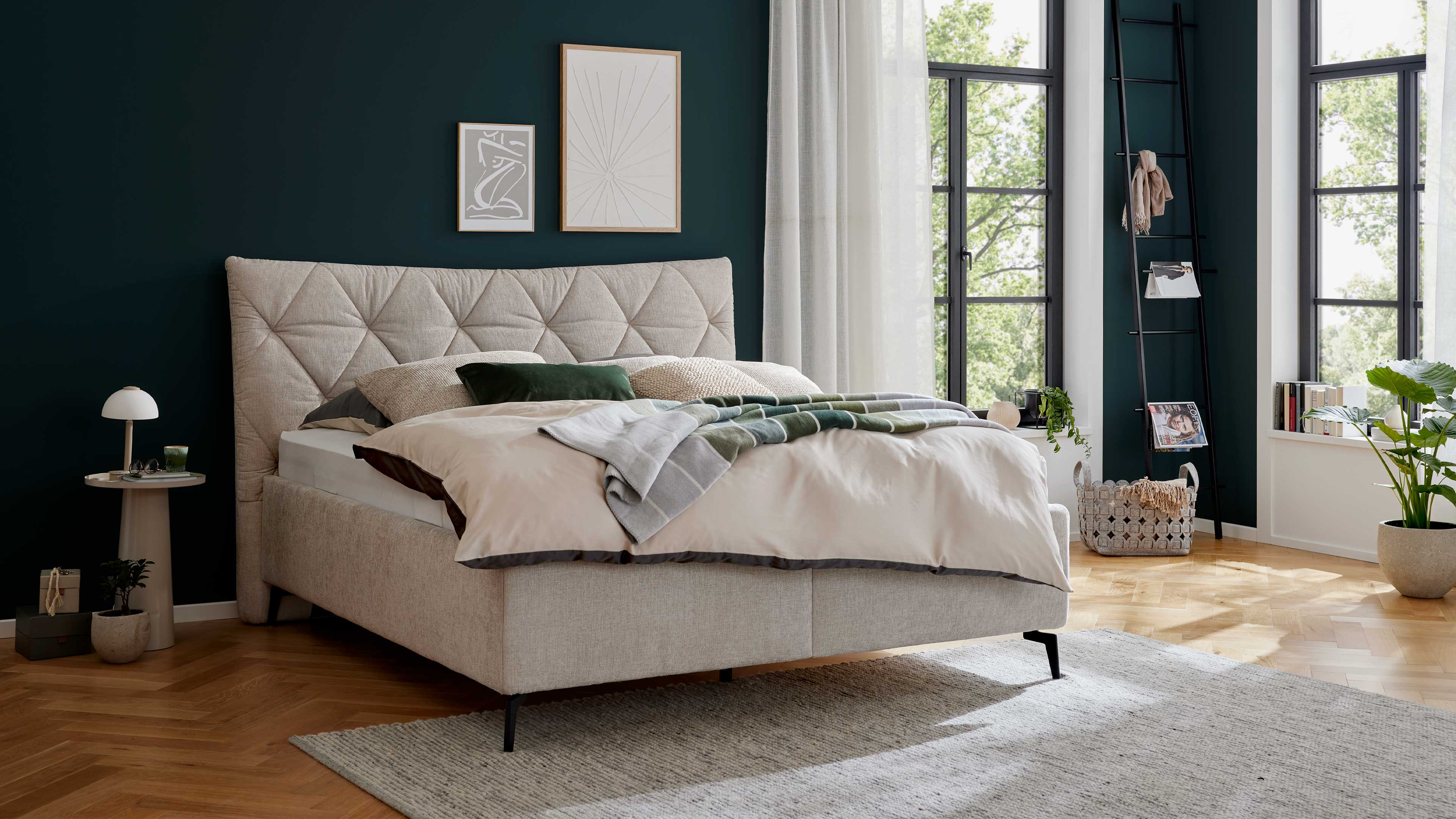 Elegantes Polsterbett in hellem Stoff mit gestepptem Kopfteil und filigranen Metallfüßen