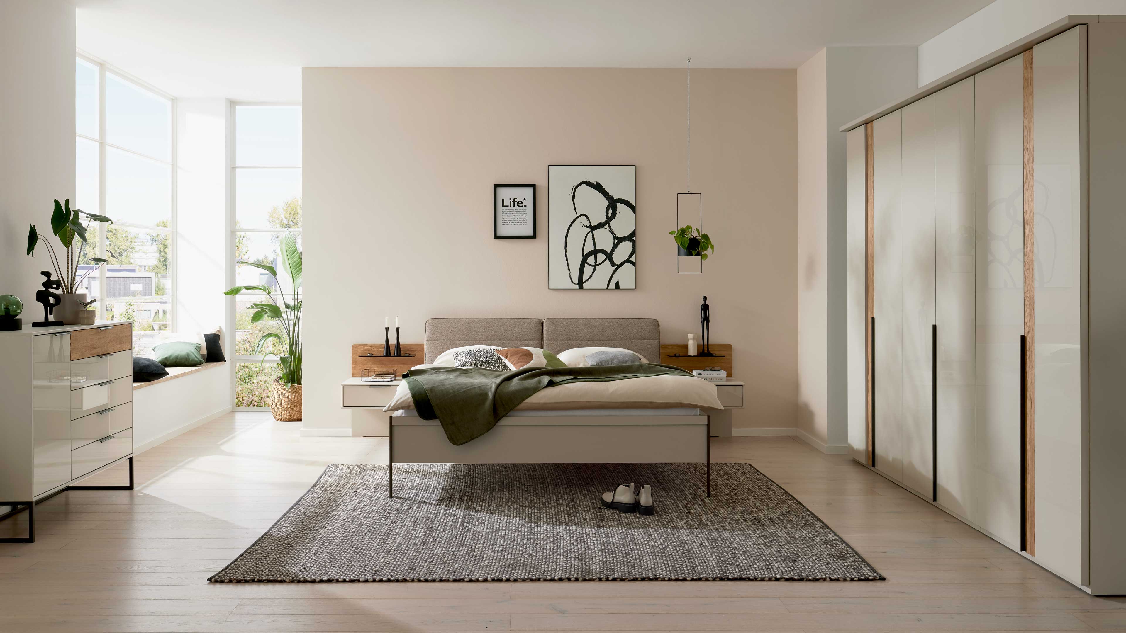 Hellgraues Schlafzimmer mit Bett, Beimöbeln und großem Kleiderschrank mit Holzakzenten und Wäschekommode