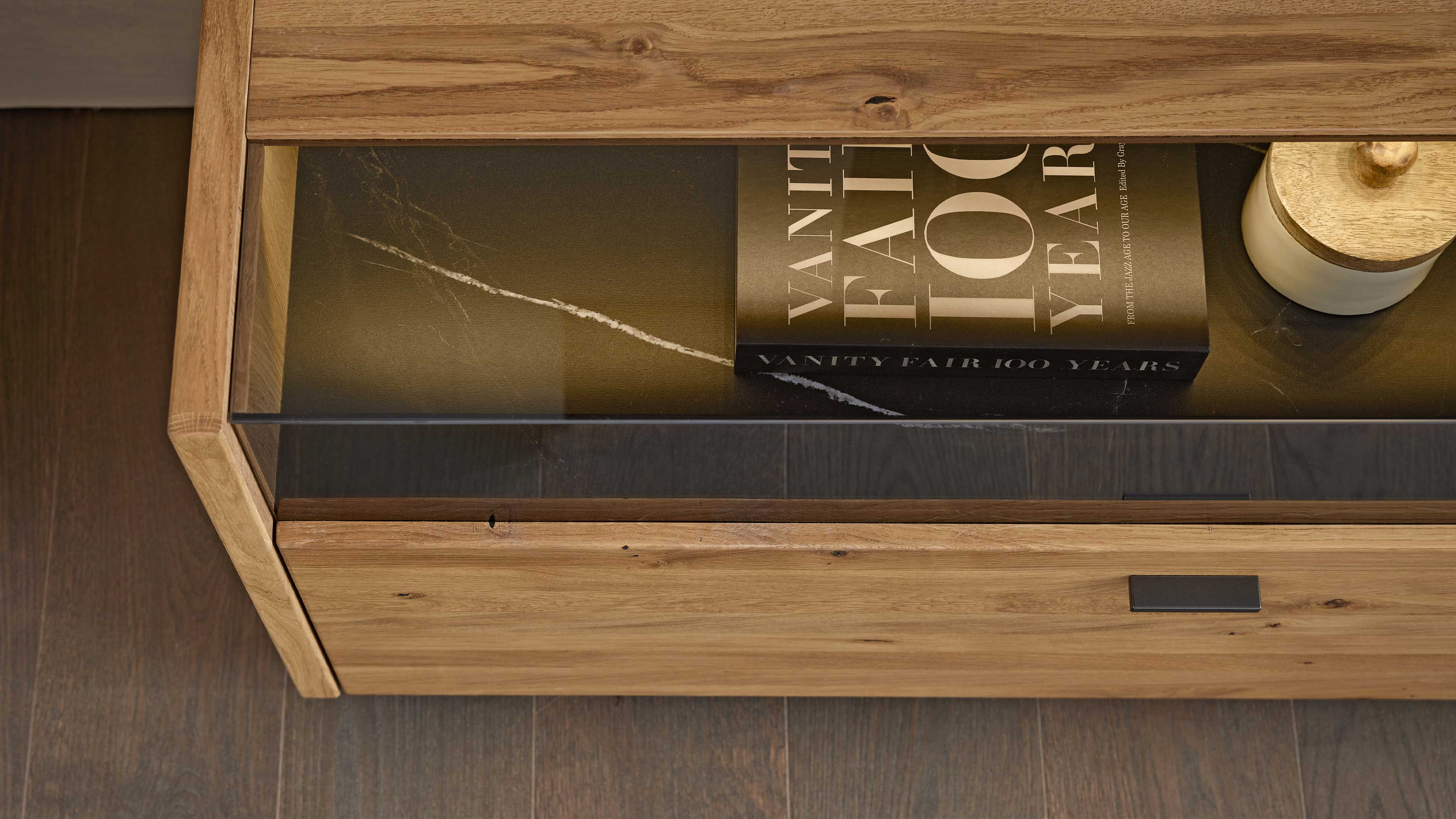 Wohnlösung mit TV-Board, hoher Vitrine und Wandregal mit grauen Glaselementen und Asteiche