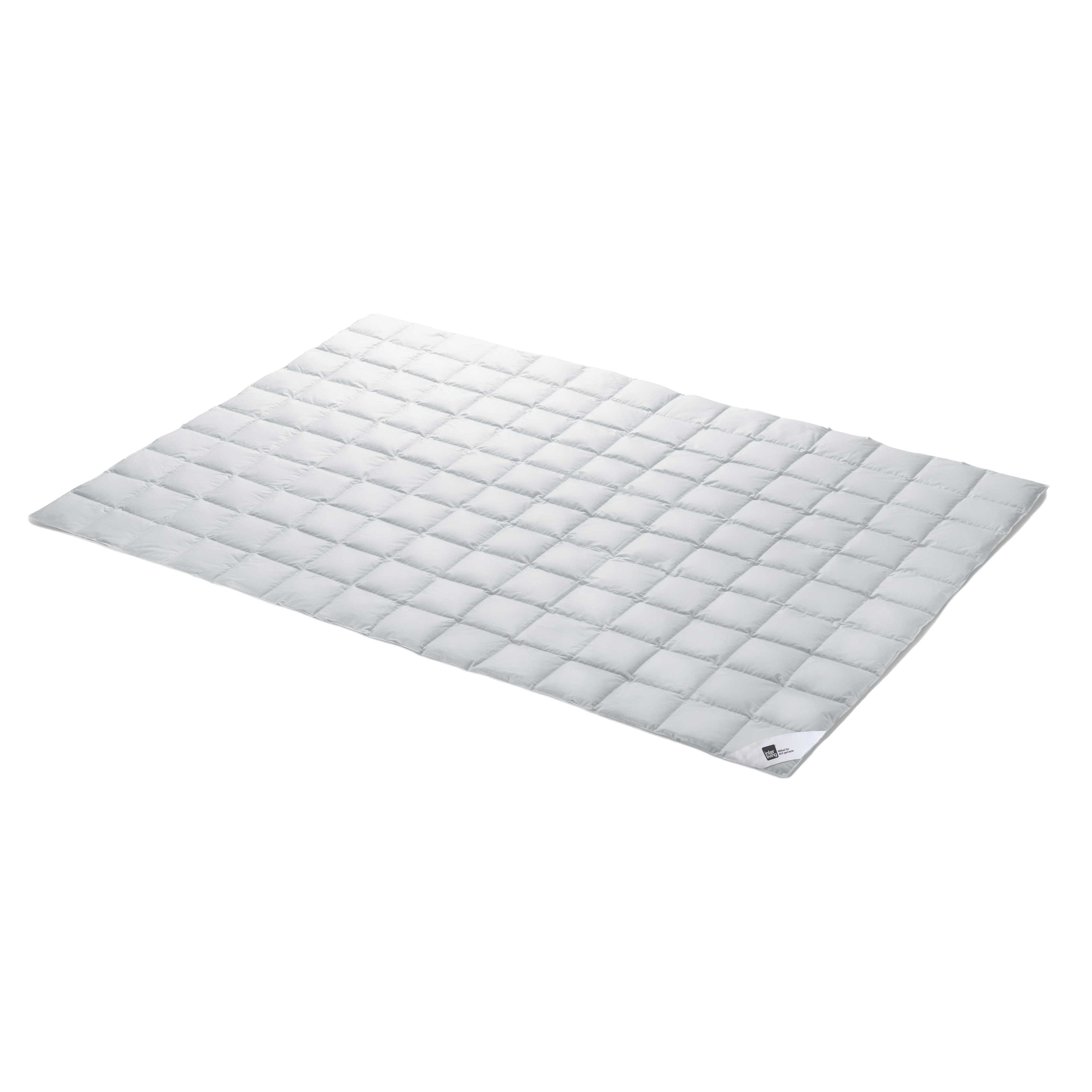 Weißer, gesteppter Bettauflage/Steppdecke mit gleichmäßigen quadratischen Kammern, flach ausgelegt und mit kleinem Etikett an einer Ecke.