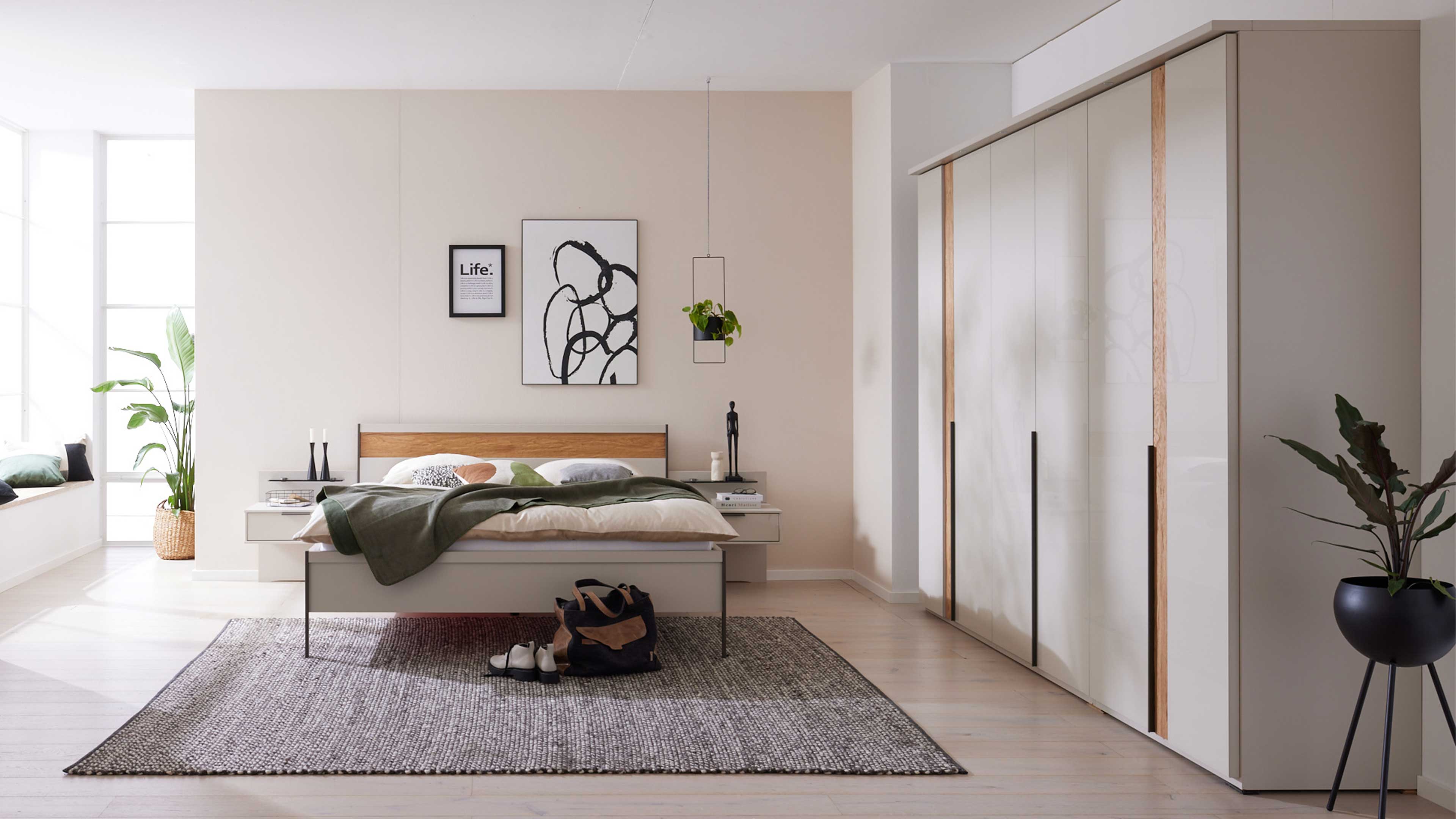 Modernes Schlafzimmer mit weißem Bett, Holzakzenten und großem Kleiderschrank in hellem Design