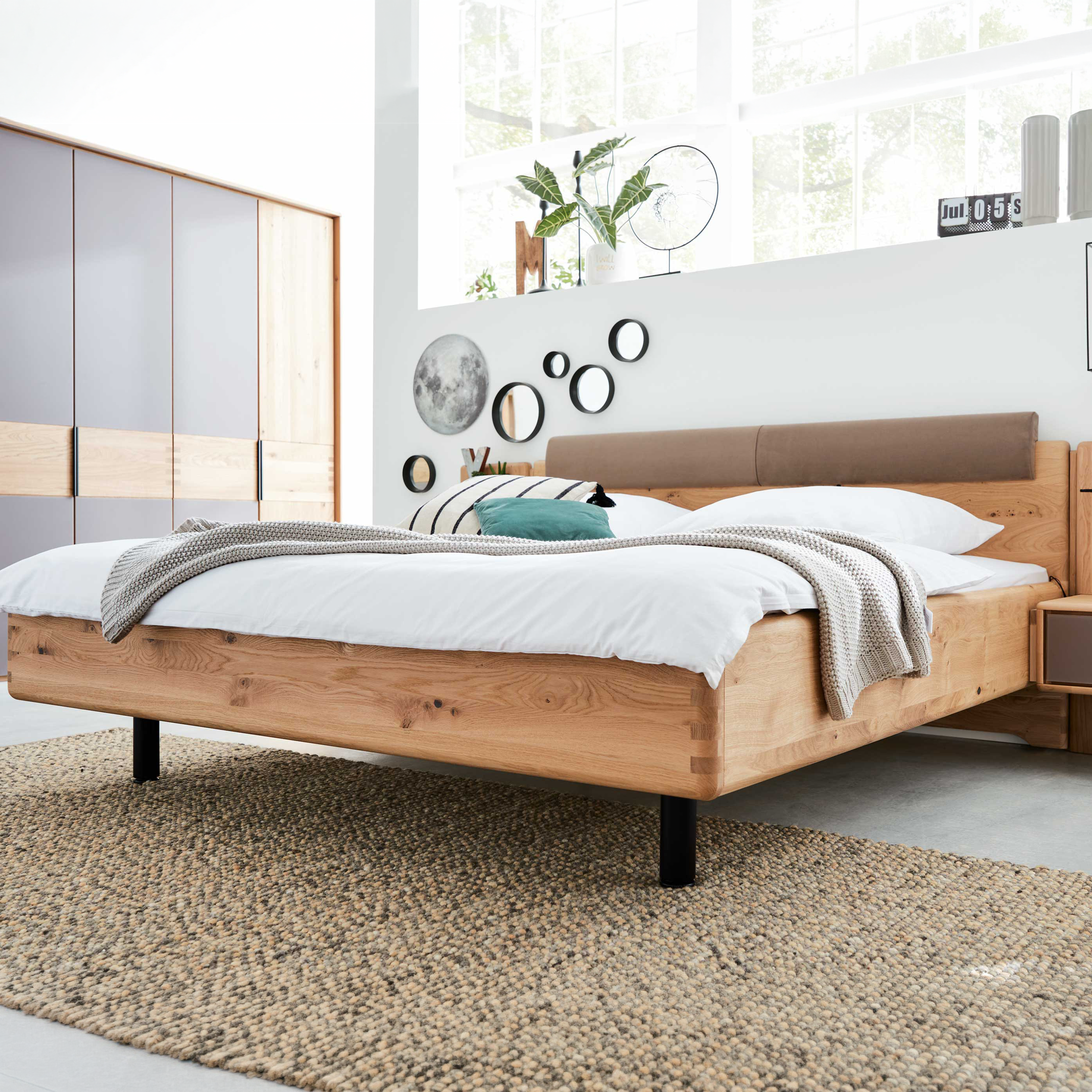 Doppelbett aus Holz mit gepolstertem Kopfteil, kombiniert mit großem Kleiderschrank und Nachttischen für ein abgestimmtes Schlafzimmer