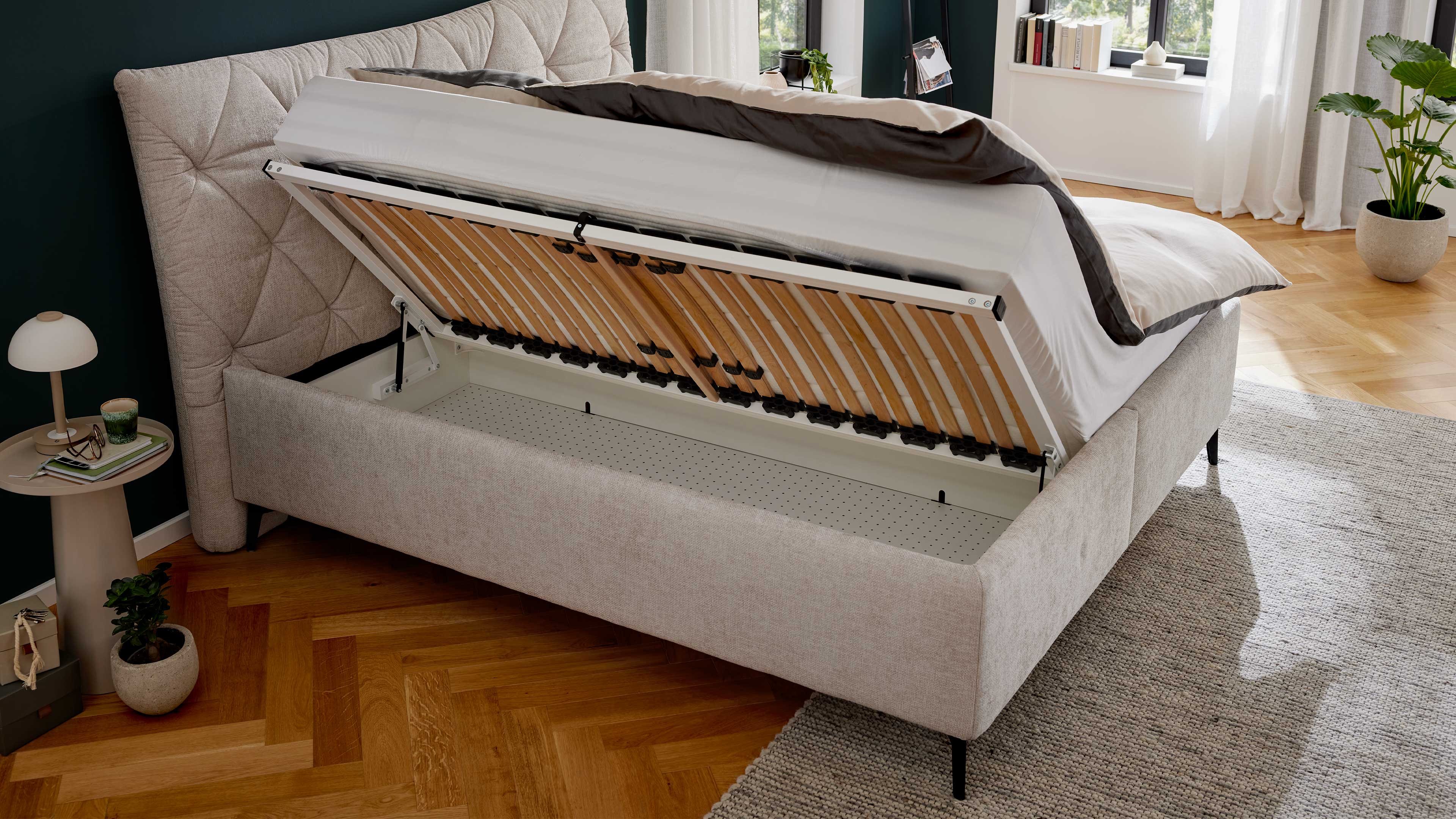 Elegantes Polsterbett in hellem Stoff mit gestepptem Kopfteil und filigranen Metallfüßen