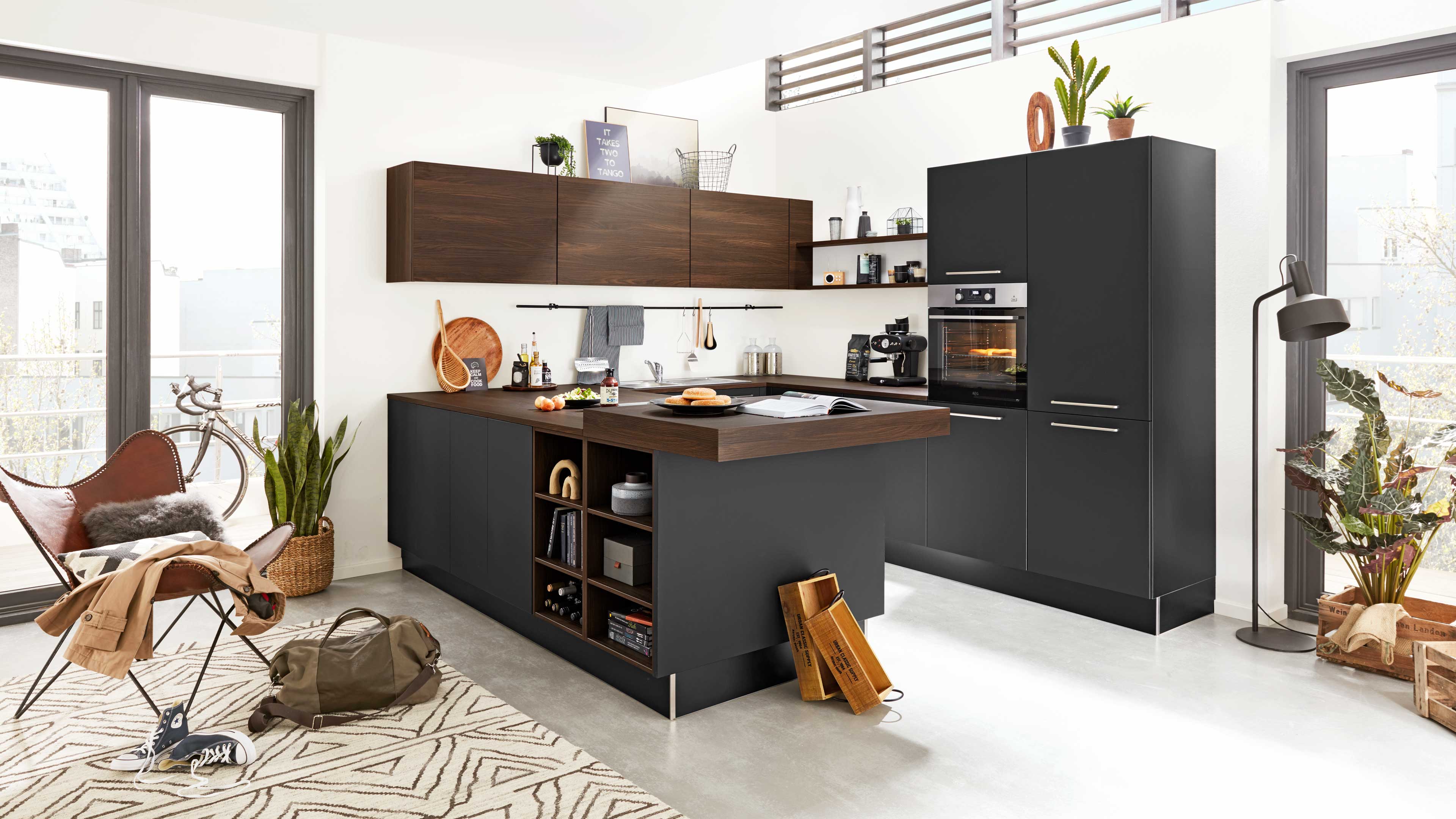 Offene Küche mit dunklen grauen Unterschränken und Holzarbeitsplatte, freistehende Insel, hoher Einbauschrank mit Ofen.