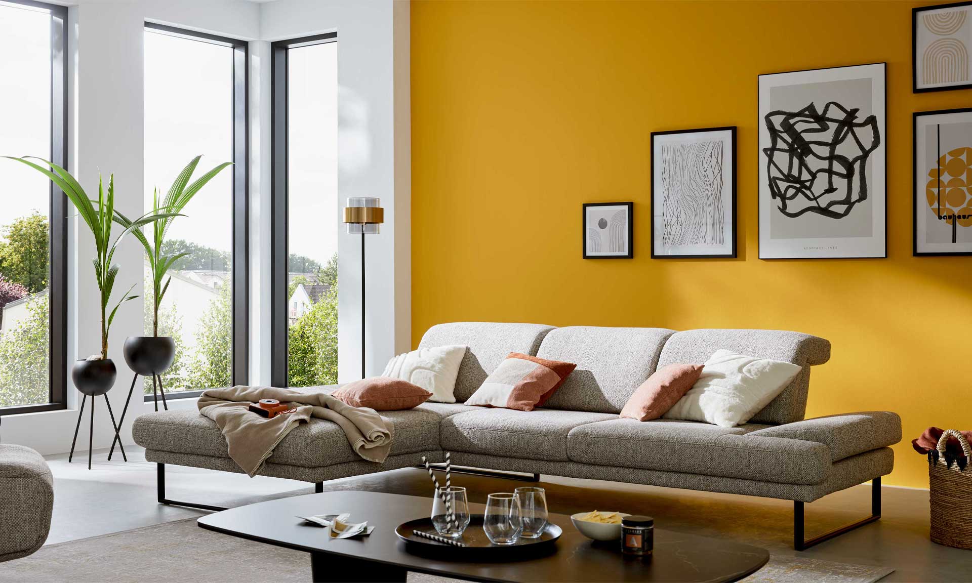 Ecksofa mit runden schwarzen Metallfüßen und Stoff in Silber