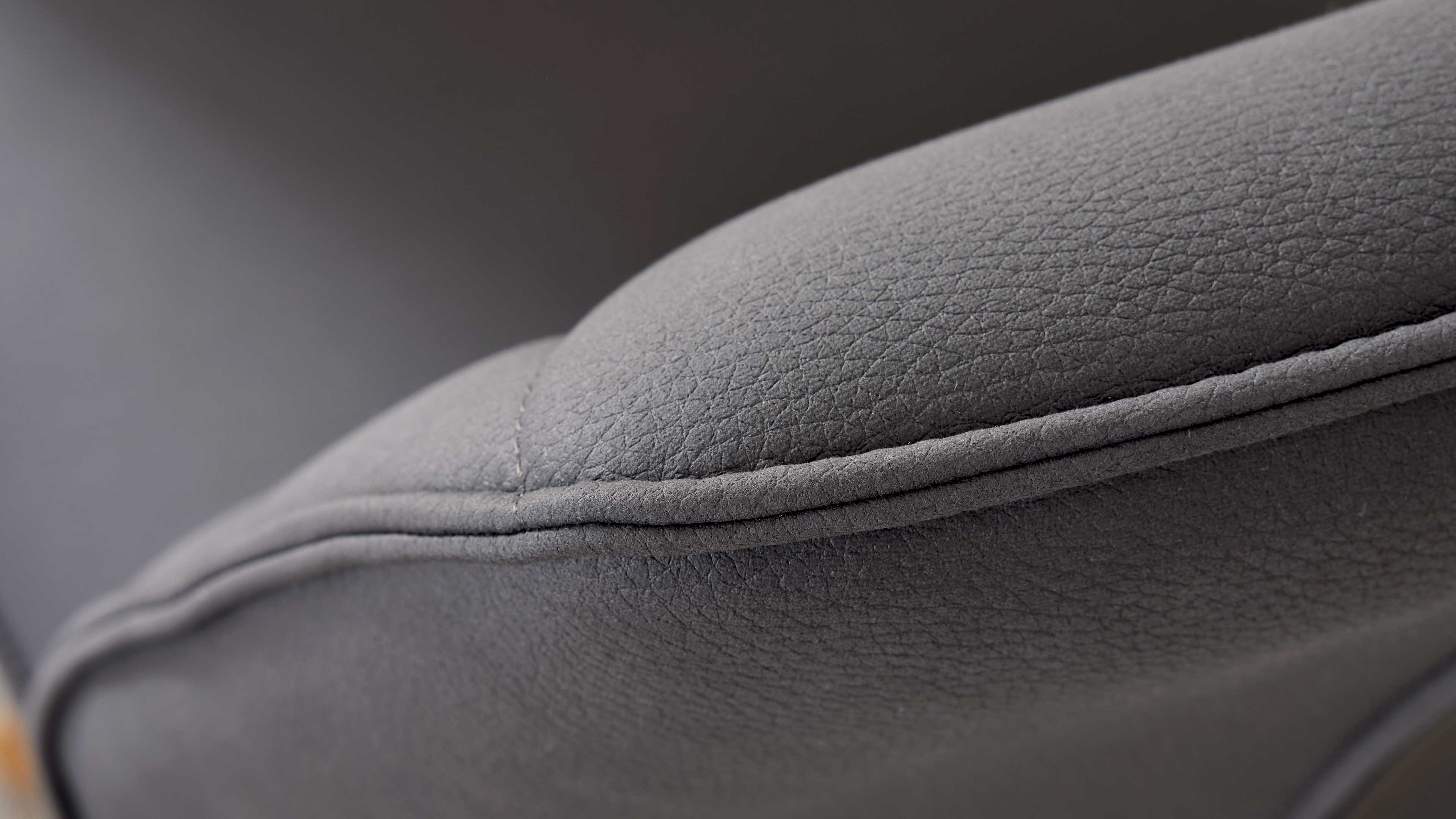 Nahaufnahme eines grauen Polsterkissens mit sichtbarer Doppelnaht und feiner Narbung auf der Oberfläche.