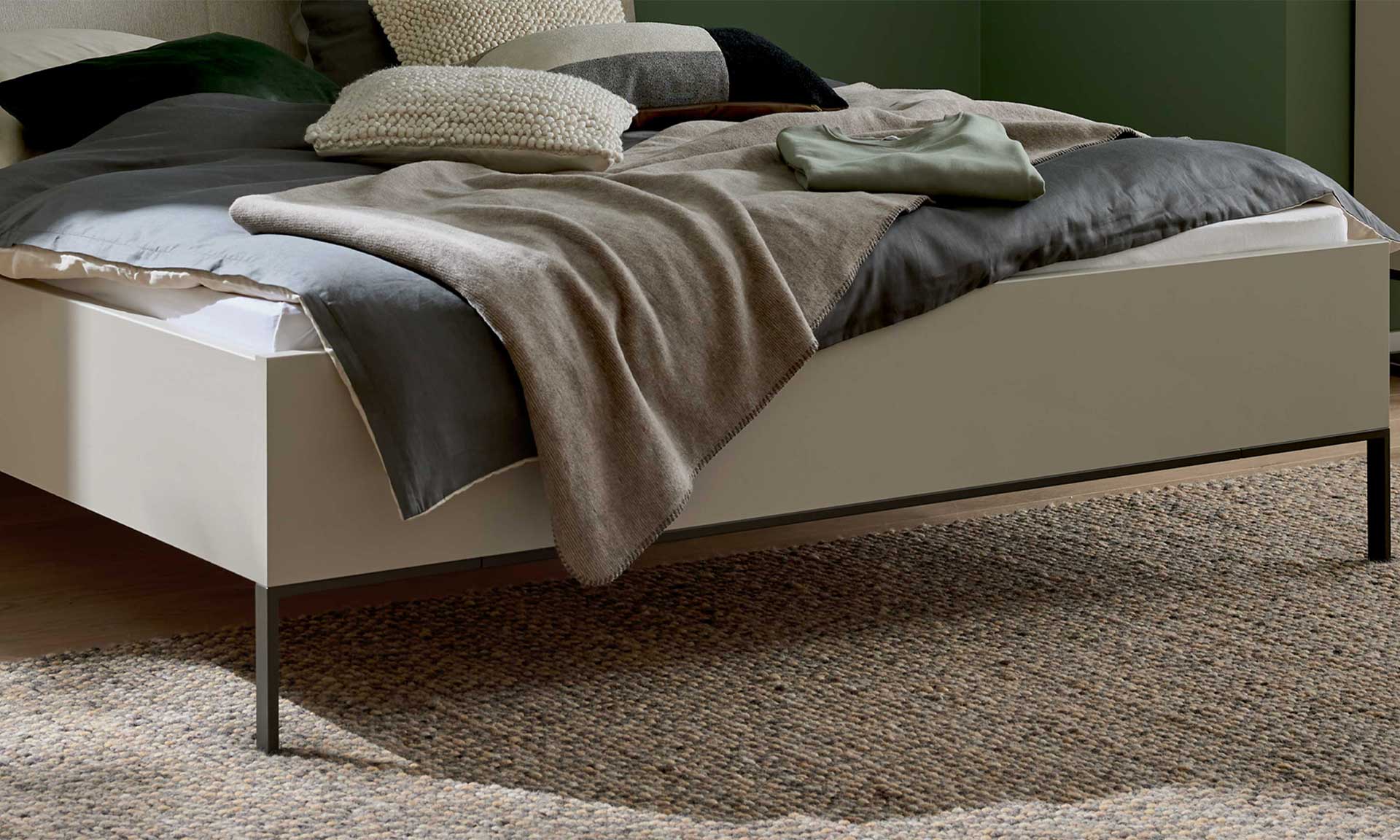 Schlafzimmer mit Doppelbett, Nachtkonsolen und Kleiderschrank in Graubeige und Kernholz