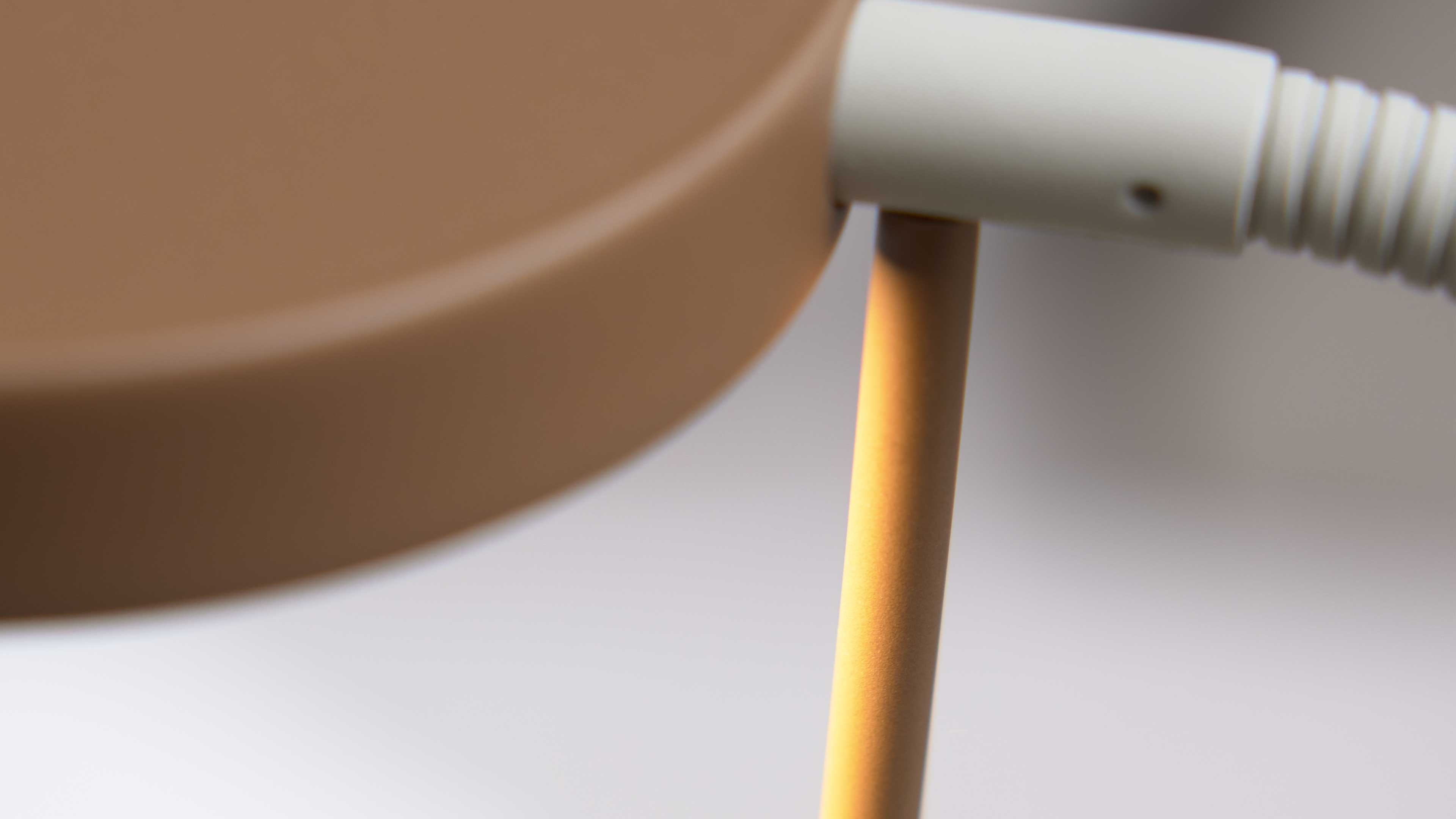 Runde braune Scheibe an einem gelb lackierten Stab, rechts eine weiße, gerippte Verbindungsbuchse mit kleinem Loch.