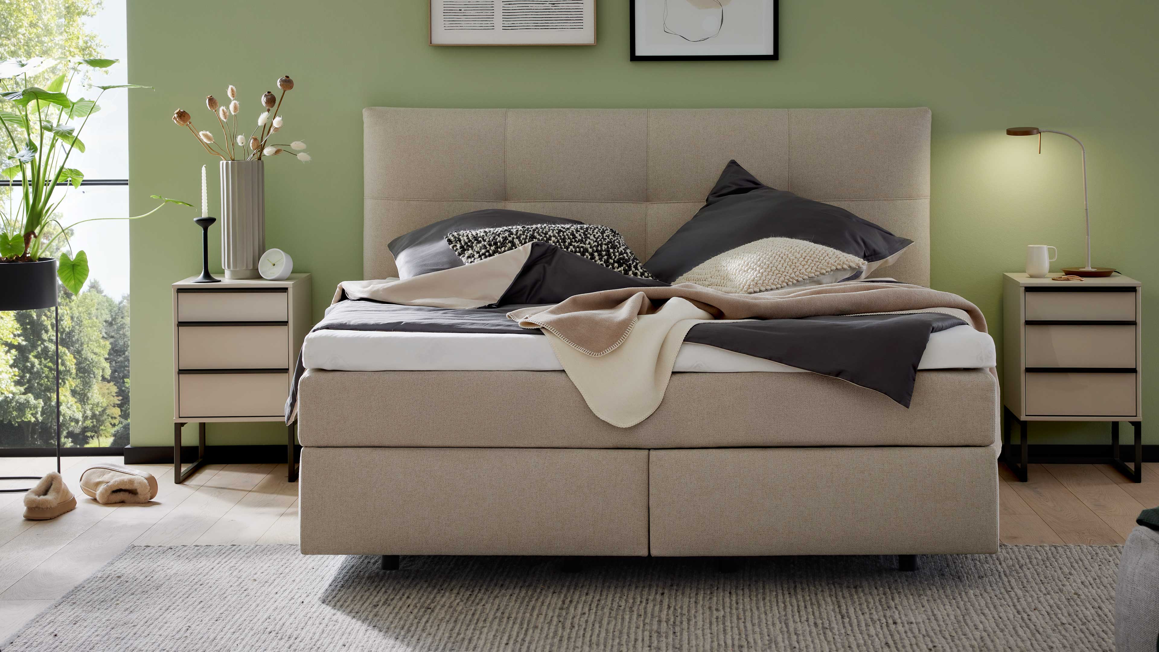 Boxspringbett mit gepolstertem Kopfteil, hellem Stoffbezug und zweiteiliger Liegefläche für gleichmäßigen Komfort