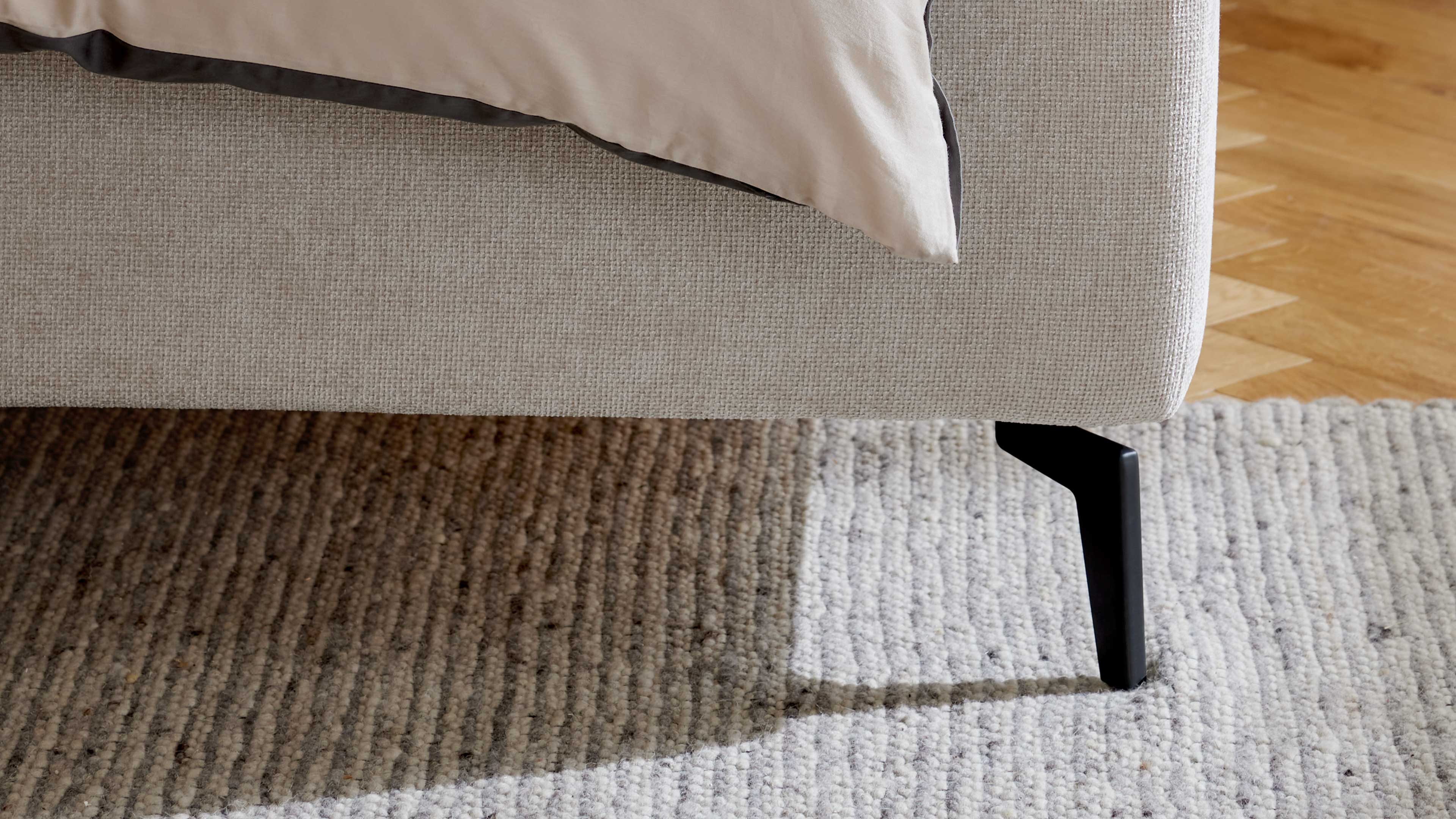 Elegantes Polsterbett in hellem Stoff mit gestepptem Kopfteil und filigranen Metallfüßen